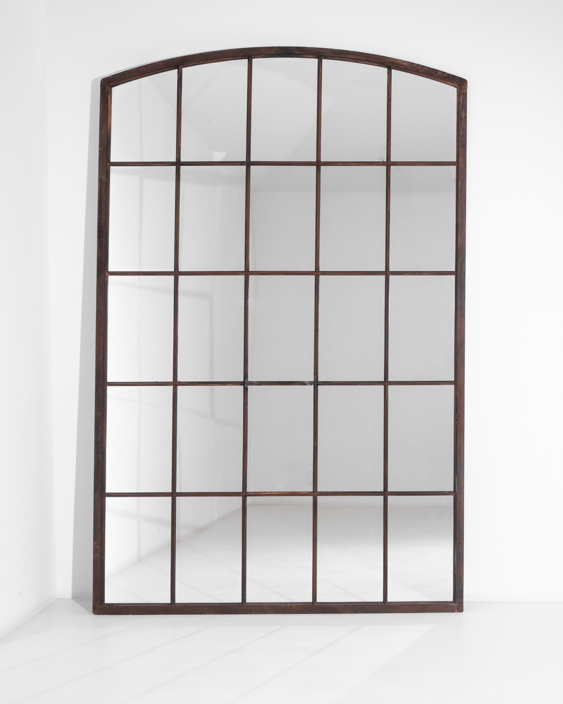 This antique metal mirror was produced in France, circa 1900. A tall mirror elevating above 100 inches, presenting a rectangular frame with a curved top. Mimicking a window structure, this sleek piece expands the perception of space through its