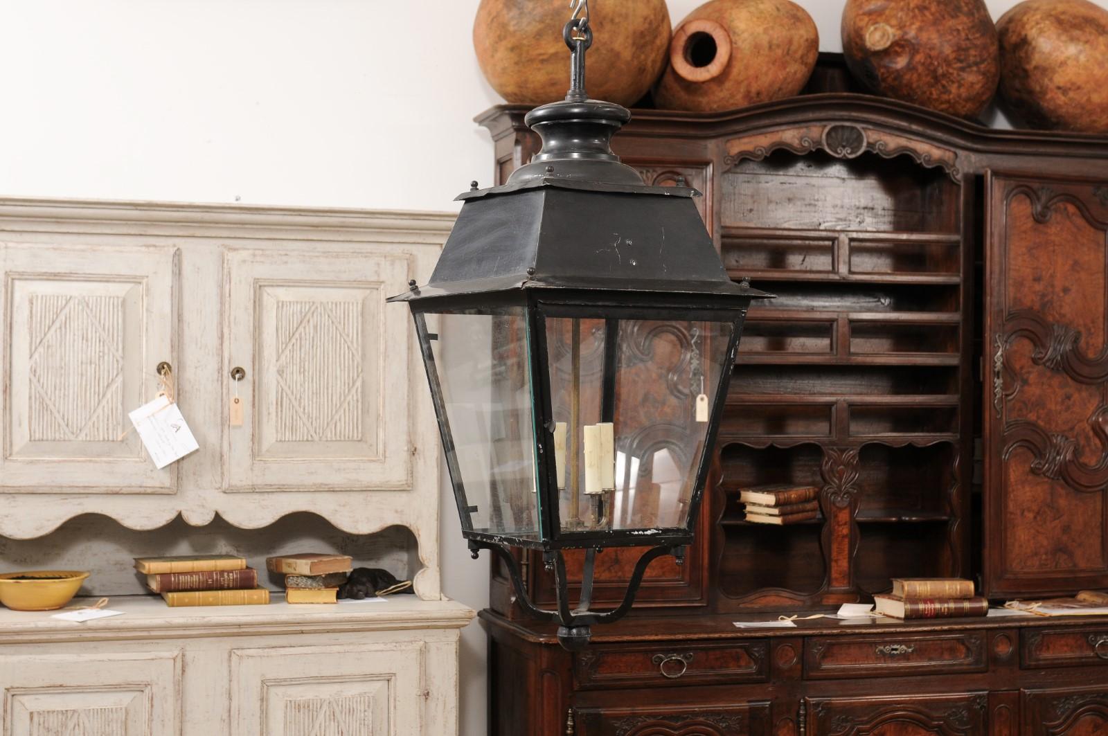Emanating the graceful elegance of early 20th-century French design, this iron lantern from circa 1900 seamlessly blends utility with artistry. Meticulously crafted with four transparent glass panels framed by slender, tapering iron lines, it offers
