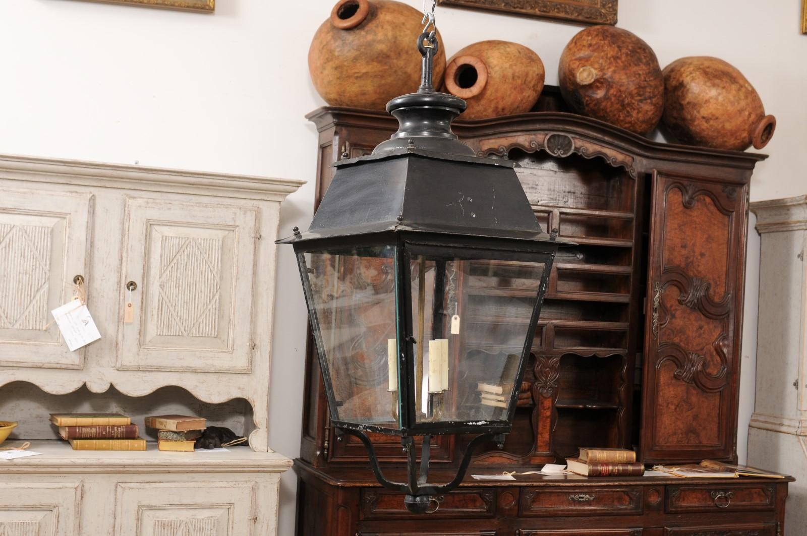 A pair of Turn of the Century French iron lanterns from circa 1900 with glass panels and wall brackets. Emanating the graceful elegance of early 20th century French design, this pair of iron lanterns from circa 1900 seamlessly blends utility with