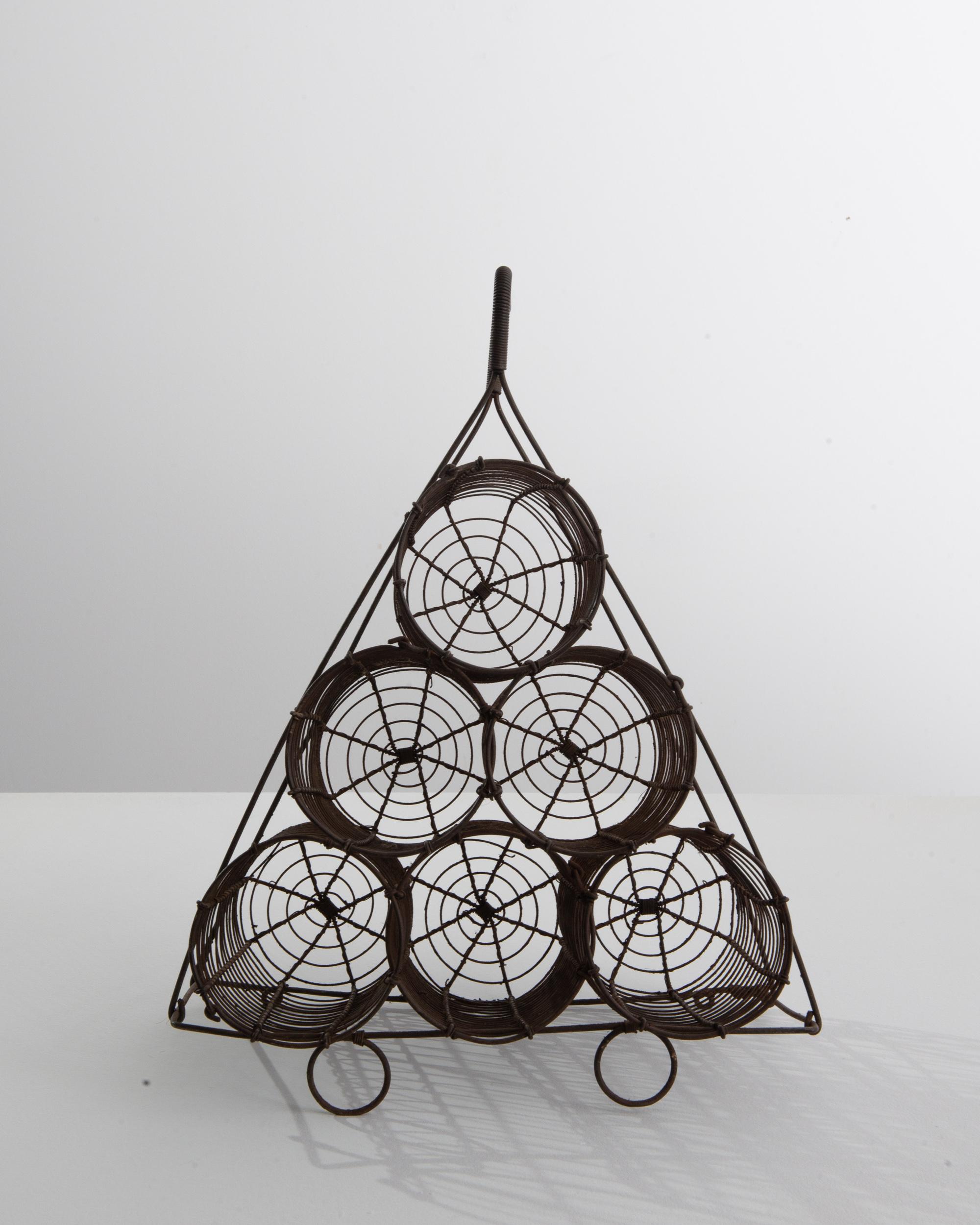 Light yet sculptural, this wire wine rack offers a unique vintage accent. Made in turn of the century France, the design has an Industrial charm —the wire cylinders evoke the forms of propellers or the coils of electrical circuits. The pyramidal