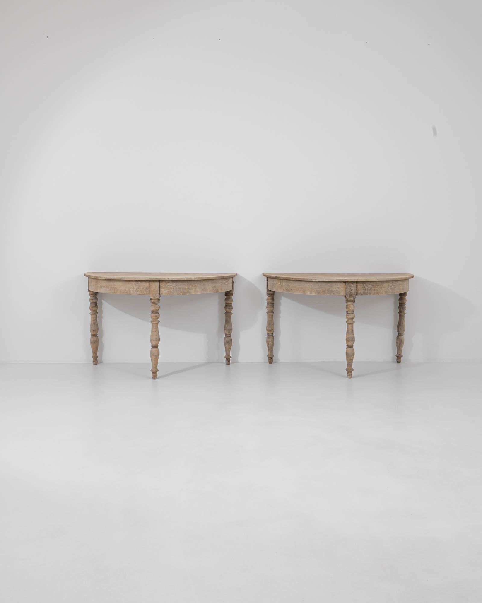 Versatile and refined, this pair of console tables in natural oak provide an elegant vintage accent. Built in France at the turn of the century, the astute design allows the semi-circular tables to be stationed independently or placed together to