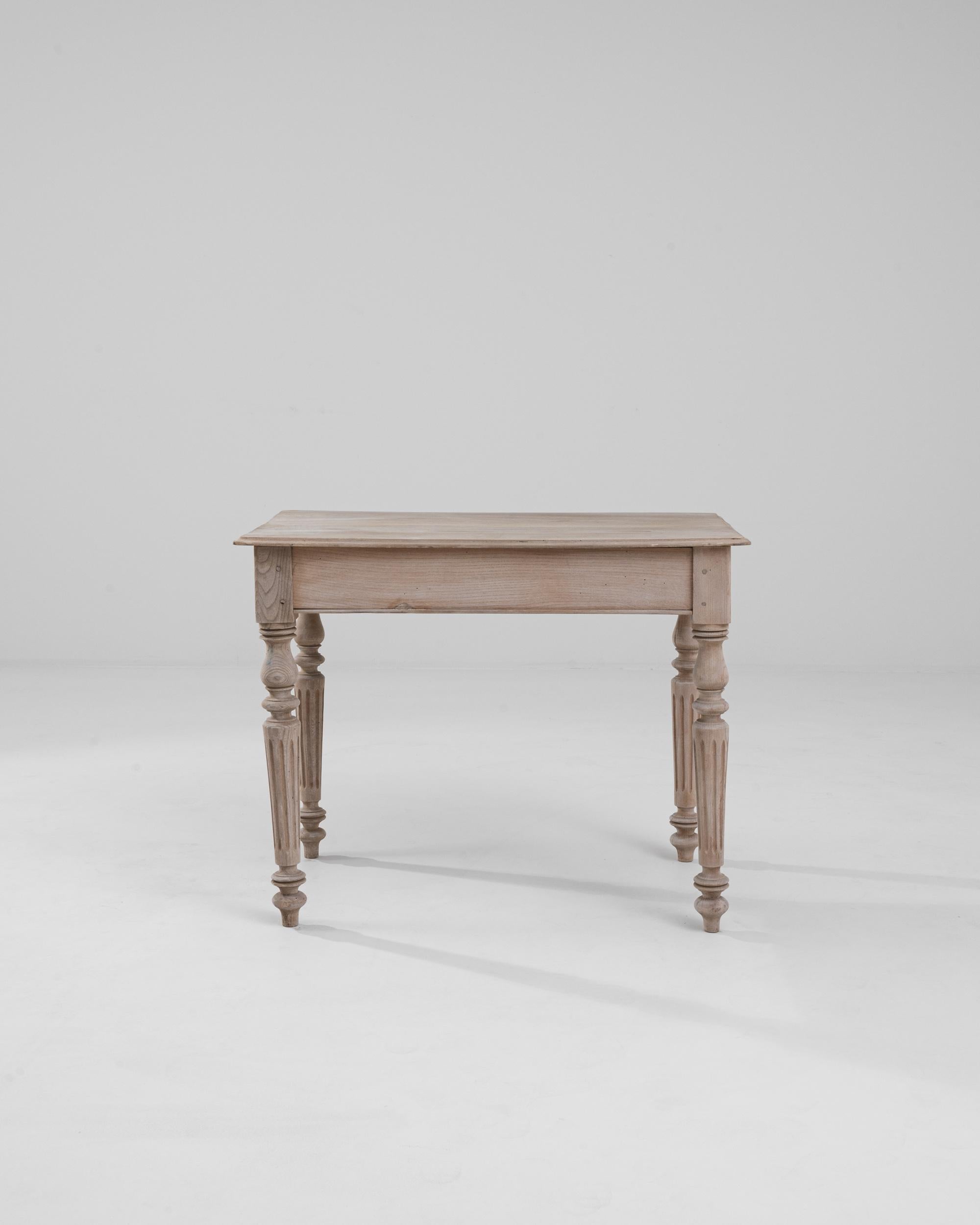 This vintage oak side table offers a graceful silhouette in natural oak. Made in France at the turn of the century, the design incorporates Neoclassical elements into a restrained and balanced composition. Fluted, tapered legs create an elegant