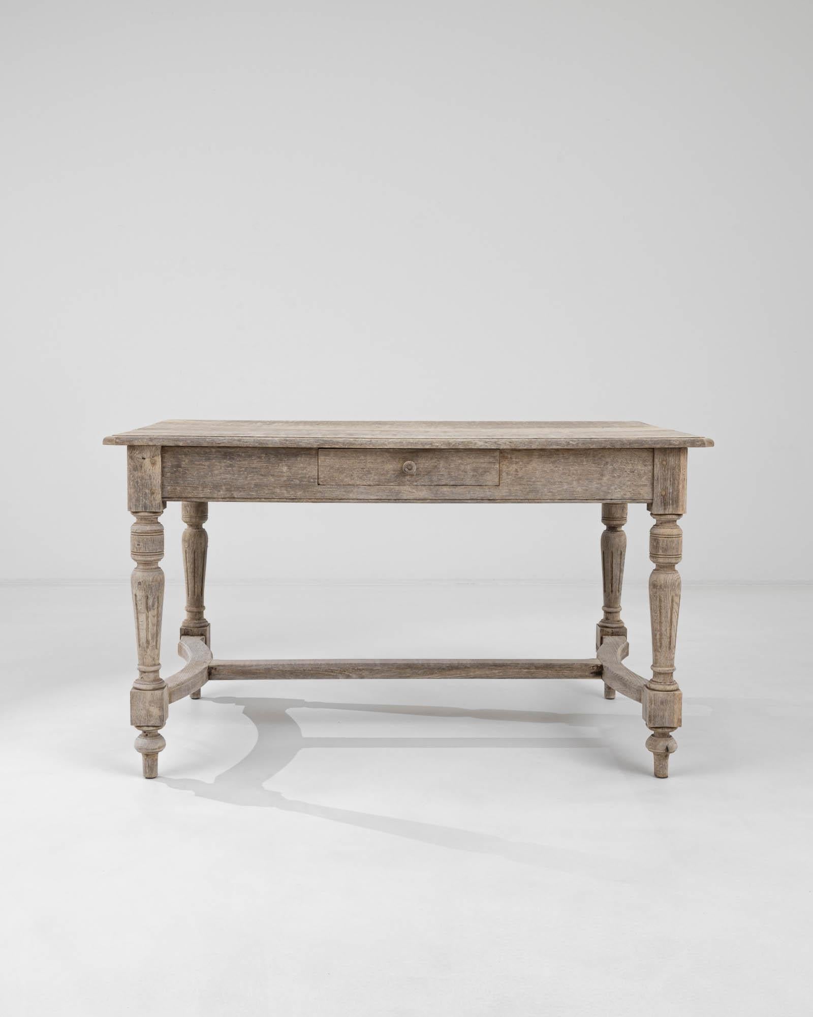 This vintage table in natural oak offers an attractive centerpiece. Built in France at the turn of the century, tapered, fluted legs create a graceful profile, lending a note of Neoclassical elegance to the Provincial design. The curved contours of