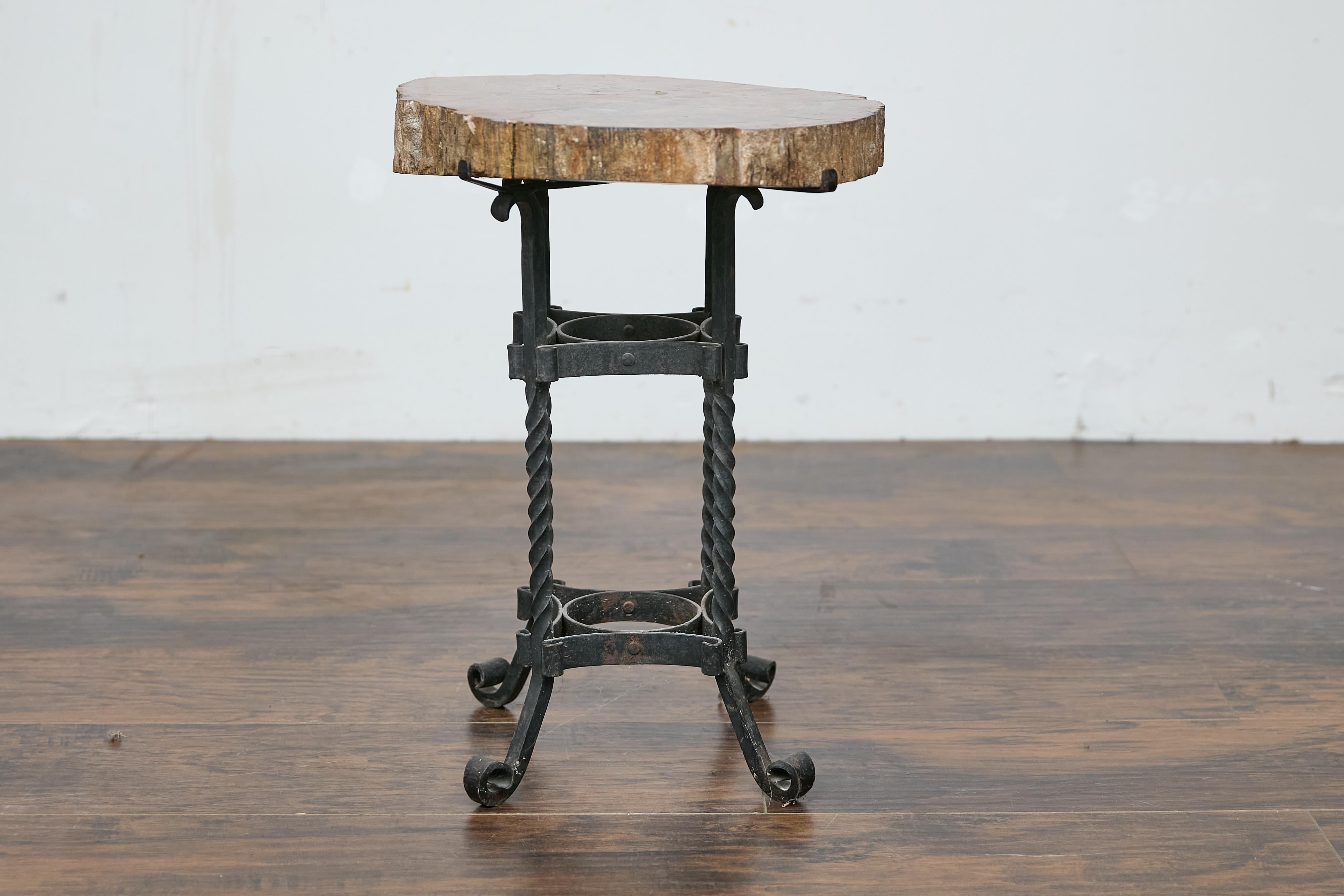 Table d'appoint en bois pétrifié du début du siècle, circa 1900, avec base quadripode en fer forgé. Cette table d'appoint française du début du siècle, fabriquée vers 1900, présente un captivant plateau en bois pétrifié qui repose élégamment sur une