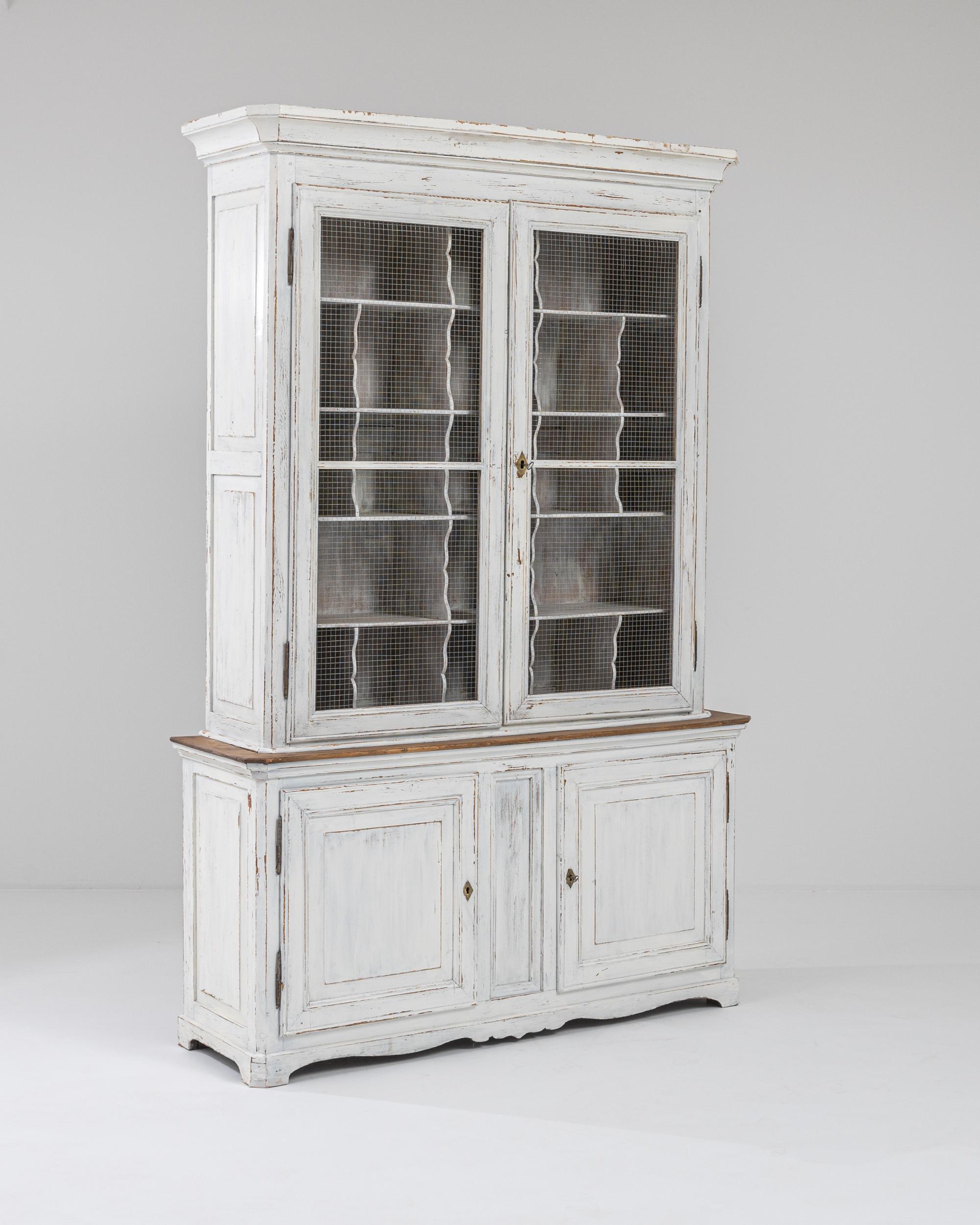 This Provincial wooden cabinet combines a unique design with a nostalgic patina to enchanting effect. Made in France at the turn of the century, the metal grill which fronts the upper cabinet indicates that this piece would have originally been used