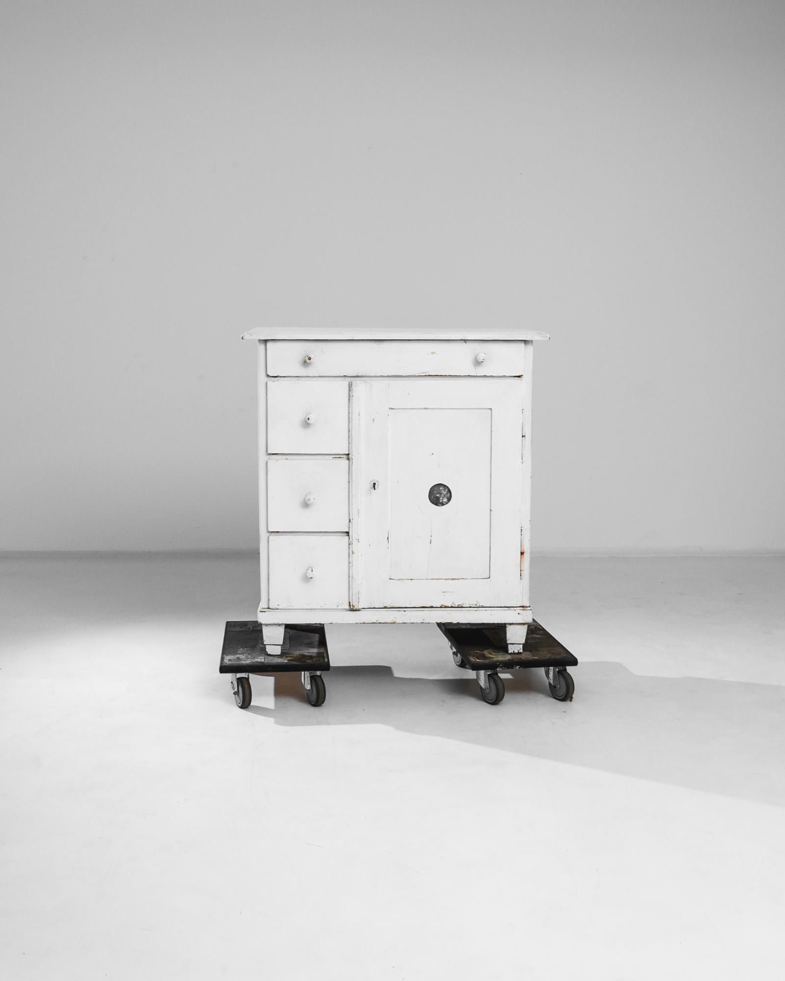 This white wooden buffet was produced in France, circa 1900. A functional small buffet standing on block feet, featuring an arrangement of four drawers and a locking front door with its original key. The door displays a charcoal circle detail