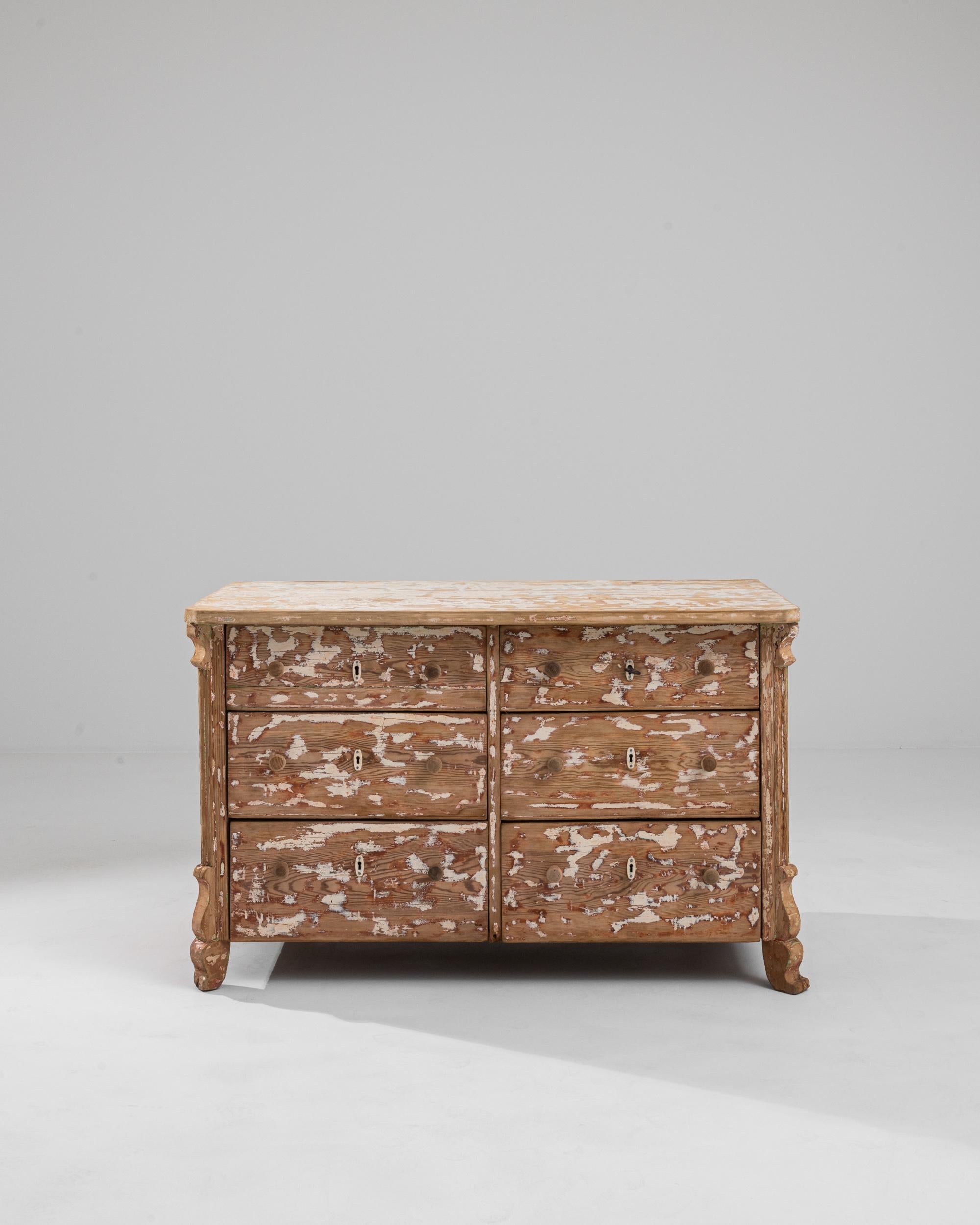 An expressive patina gives this vintage wooden chest of drawers a unique personality. Built in France at the turn of the century, the original painted finish has been scraped away to create a variegated pattern of cream and russet patches atop the
