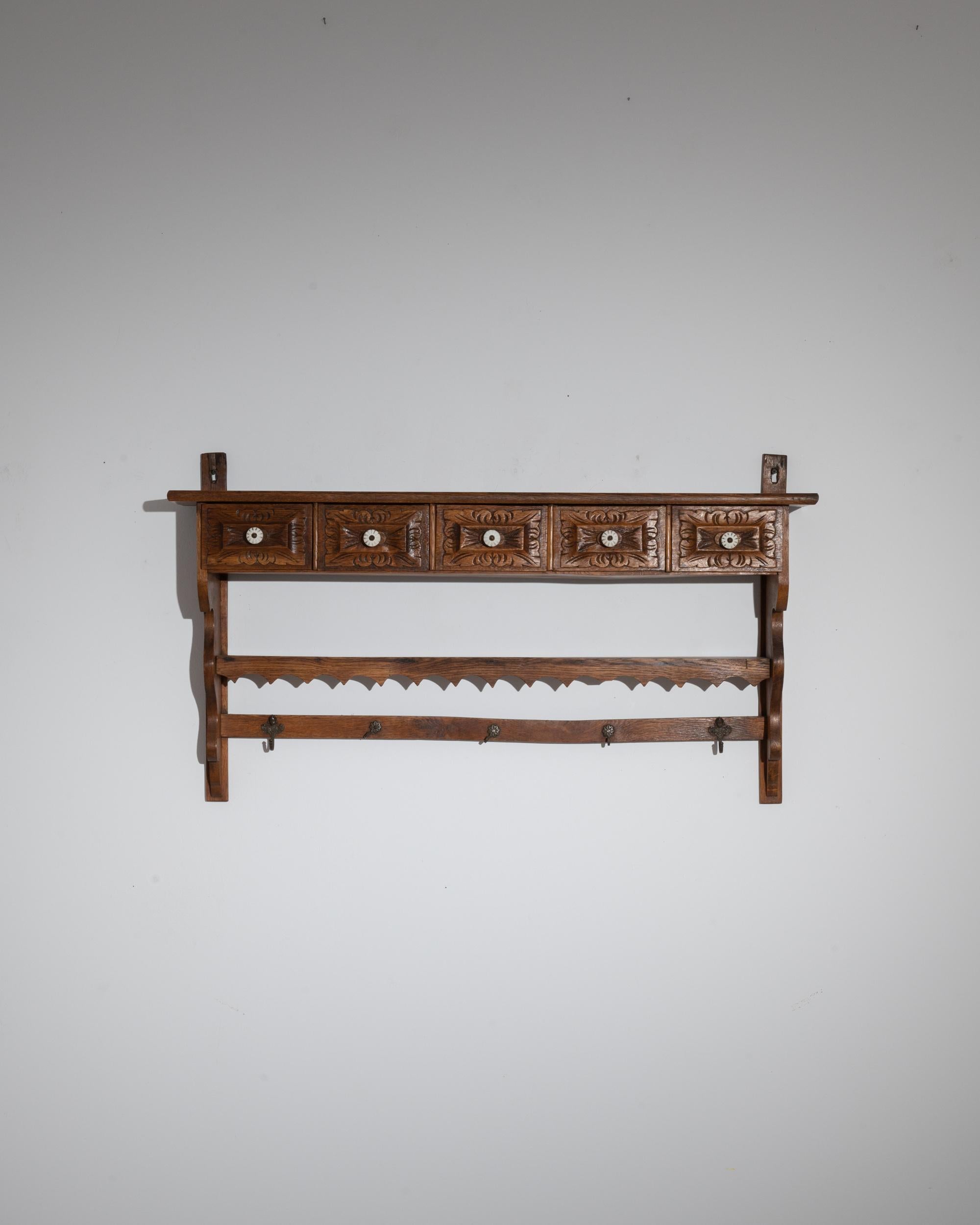 This vintage wooden wall shelf offers a pragmatic storage solution with a charming country demeanor. Made in France at the turn of the 19th century, wooden brackets sandwich an upper shelf, a sequence of five wooden drawers and a line of metal