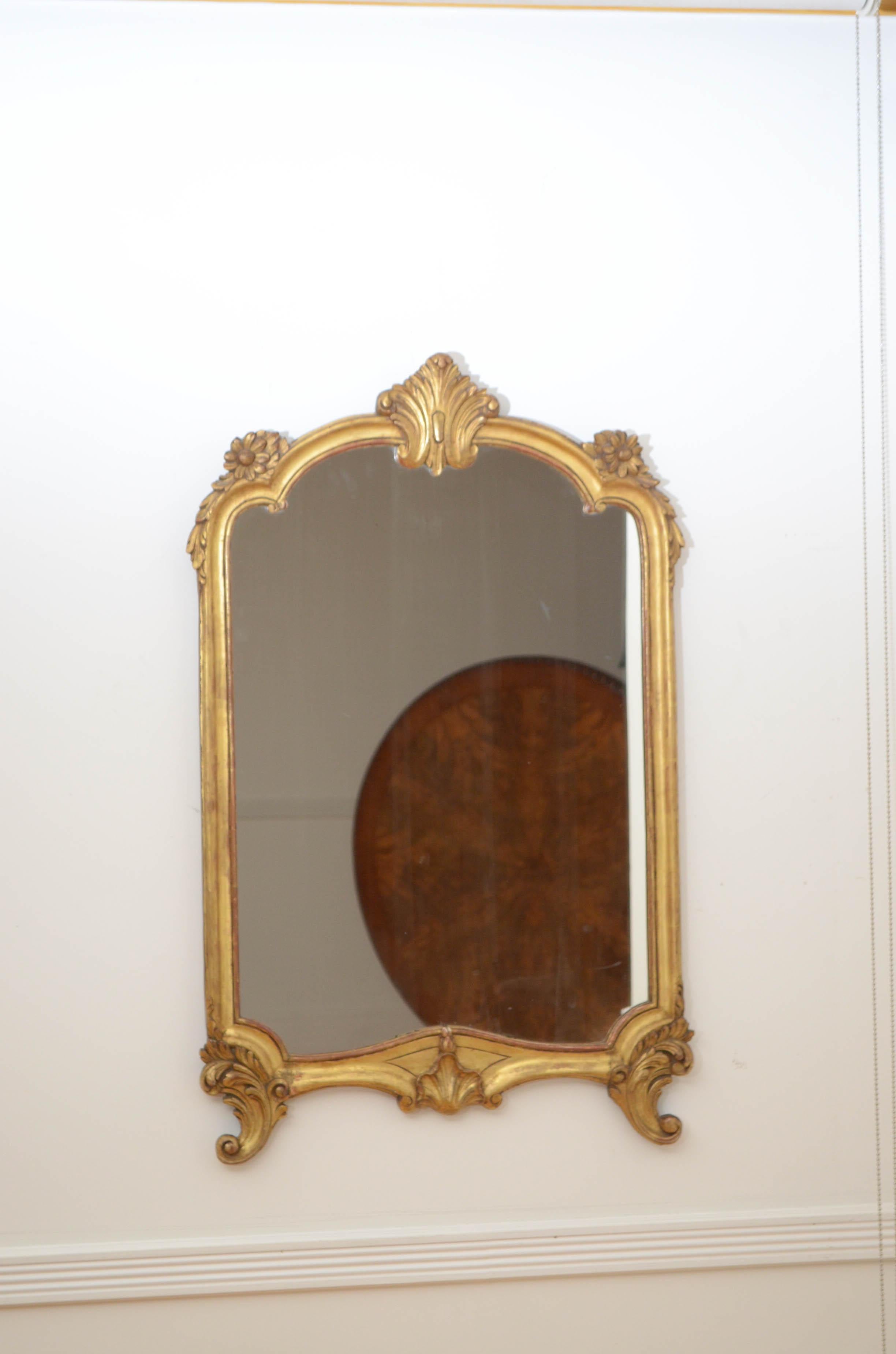 K0158 very attractive French wall mirror, having original glass with some silvering and imperfections in moulded and carved frame with leafy and floral scrolls and centre crest. This antique mirror retains its original glass, gilt and backboards,