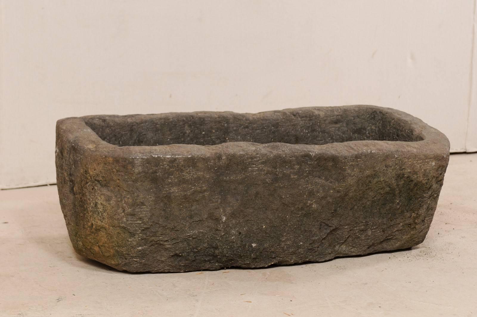 A stone trough from the turn of the 19th and 20th centuries. This antique stone trough from Indonesia is rectangular in shape and has been carved out of a single piece of stone. It is both beautiful and rustic, simplistic in design. A delightful