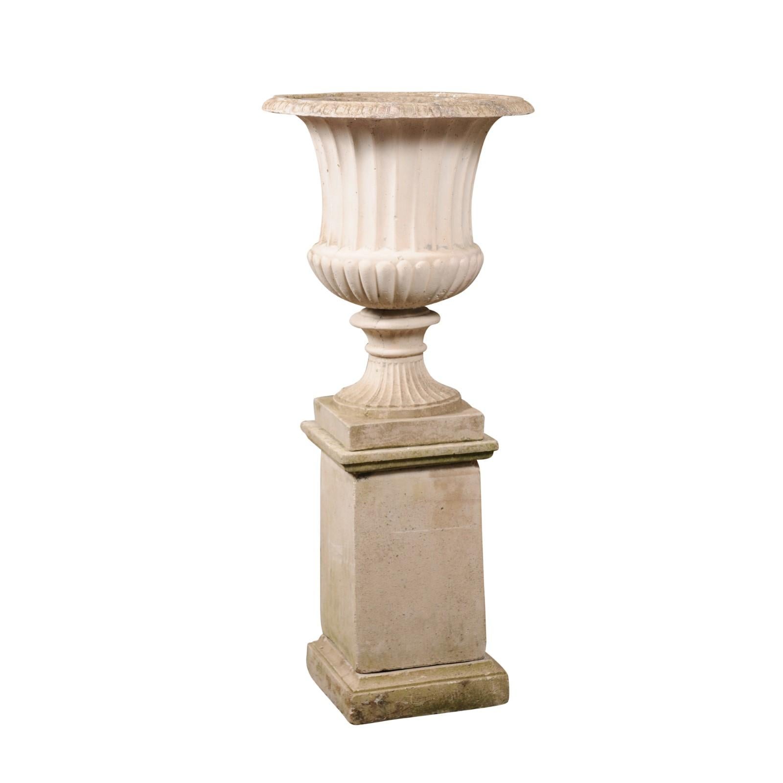An Italian turn of the century campania urn from the early 20th century, with gadroon motifs, flaring shape and tall pedestal. Made of reconstituted stone in the early years of the 20th century, this Italian Campania urn captures our attention with
