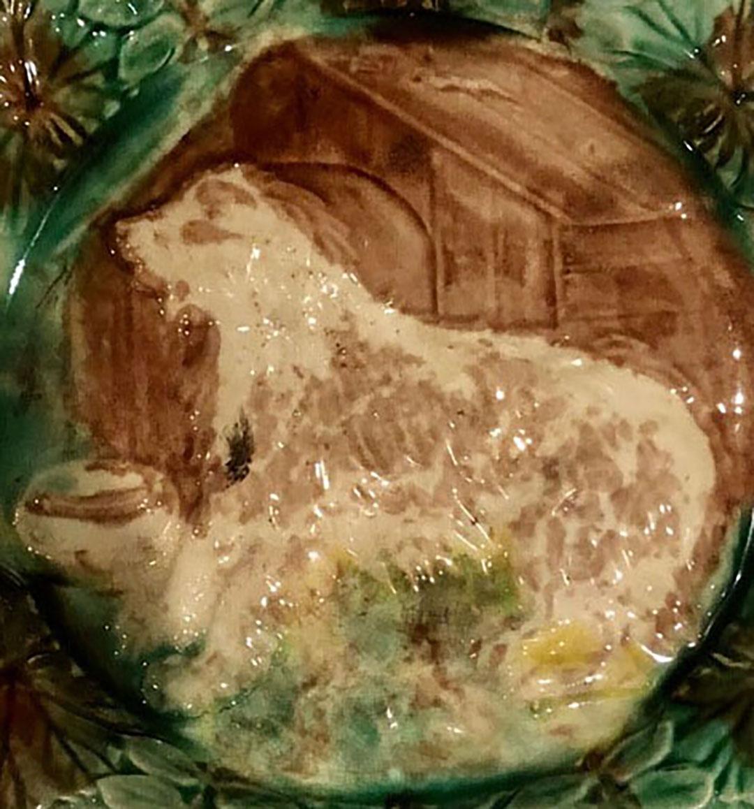 A rare majolica plate depicting a dog in a doghouse with a scalloped edge. Turn of the century maybe 1890s.