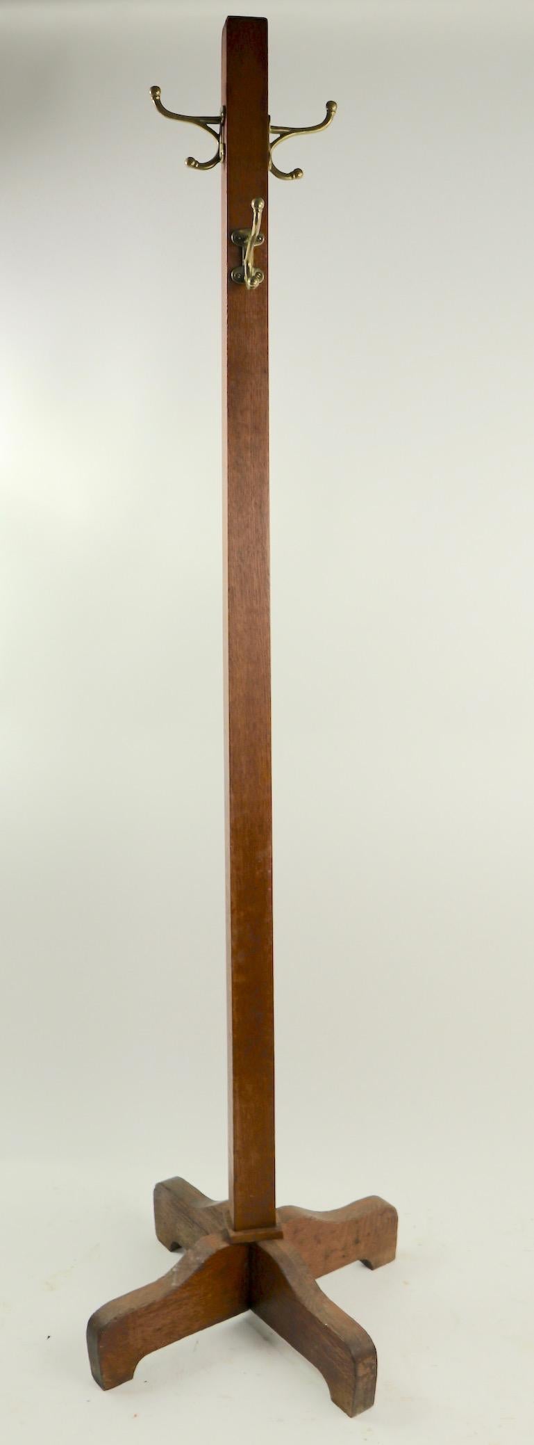 Nice sturdy and solid coat, or hat tree in oak with brass hooks. Each hook has a larger upper (coat) hook 3.5 inch, and a lower smaller hook (hats, scarves etc.) Center post 2 in. square base 21 inch W. x 9.5 inch W. at top. Well constructed and