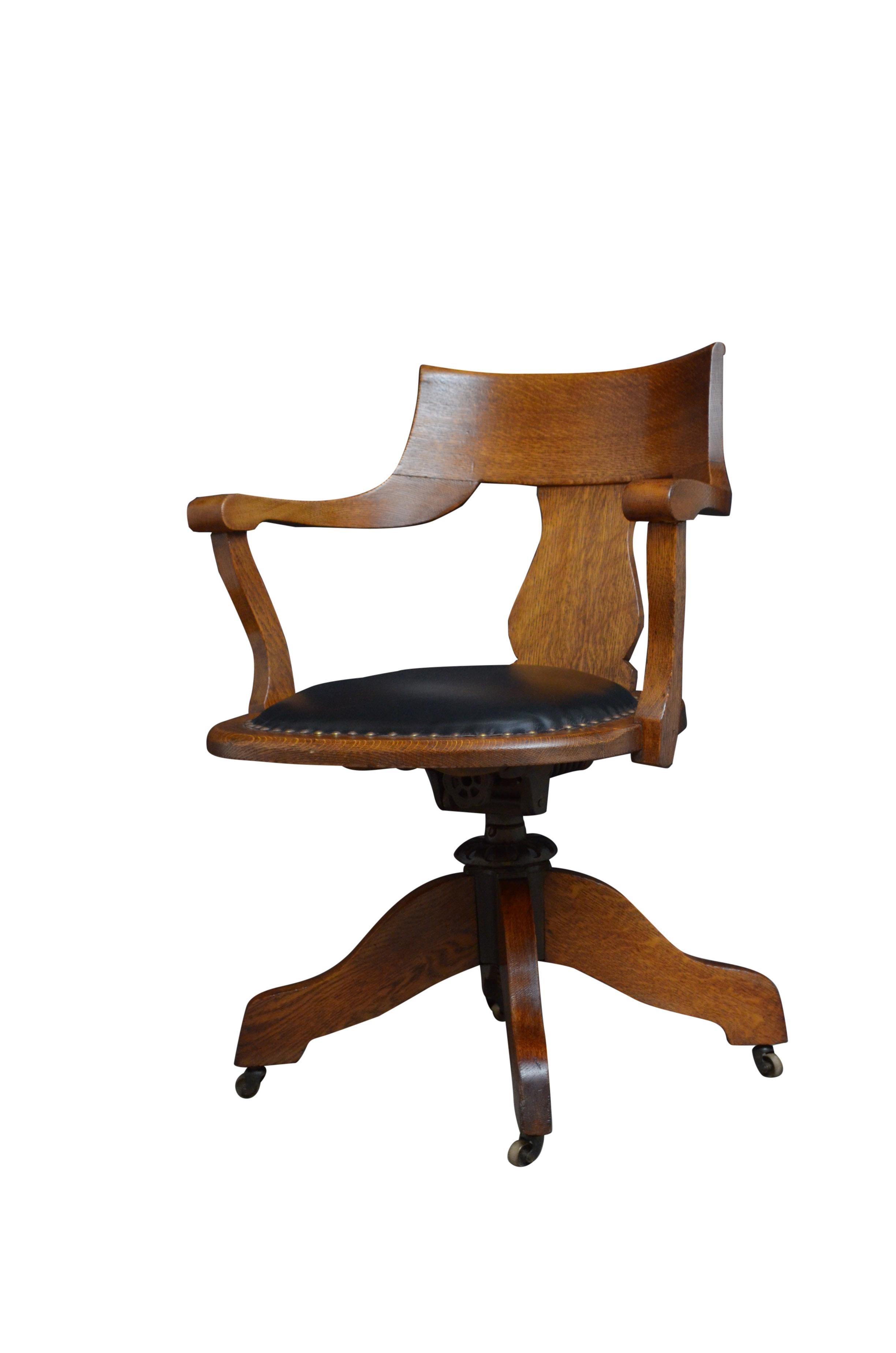 K0513 Early XXth century revolving and tilting desk chair in oak, having shaped top rails with shaped splat below, open arms and black leather seat, raised on revolving mechanism and tilting with four shaped legs terminating in original castors. The