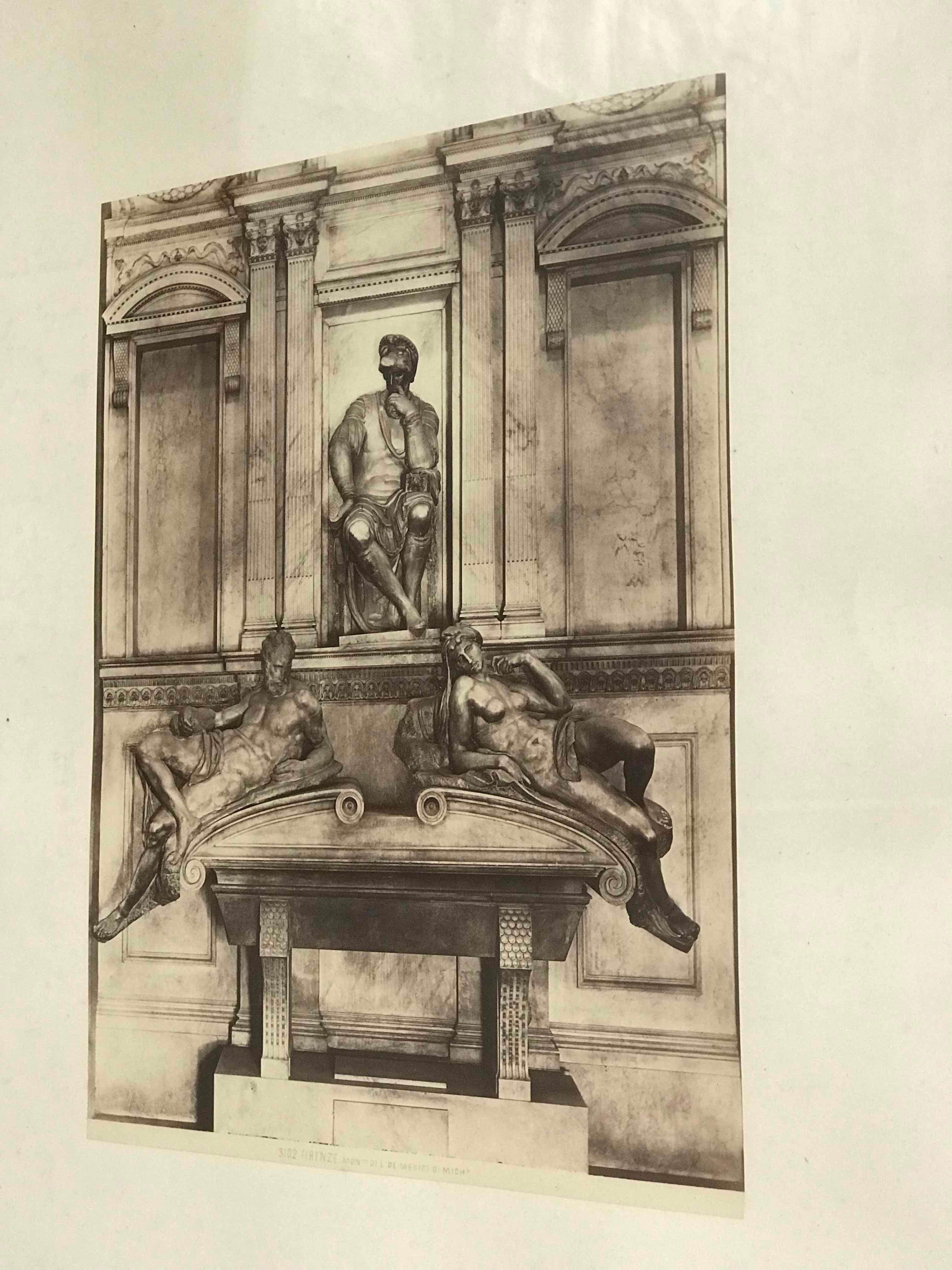 Early 20th-century black-and-white photograph of Italian architectural details from England. Mounted in a simple, softly beveled black frame, the image gives off a faint, sepia-toned glow. At the center of the image, a seated sculpture of a Roman