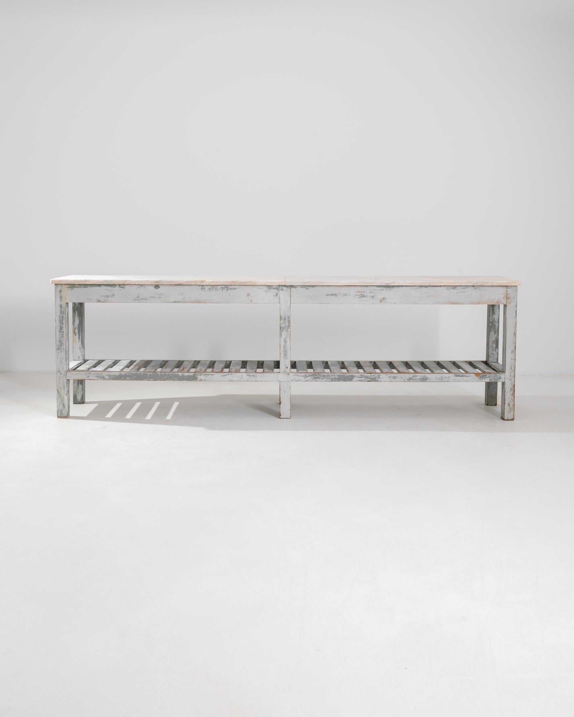 This vintage table combines a distressed patina with an elegant marble tabletop for a unique synthesis of simplicity and refinement. Made in Portugal at the turn of the century, this piece was likely originally used in a kitchen or bakery: marble
