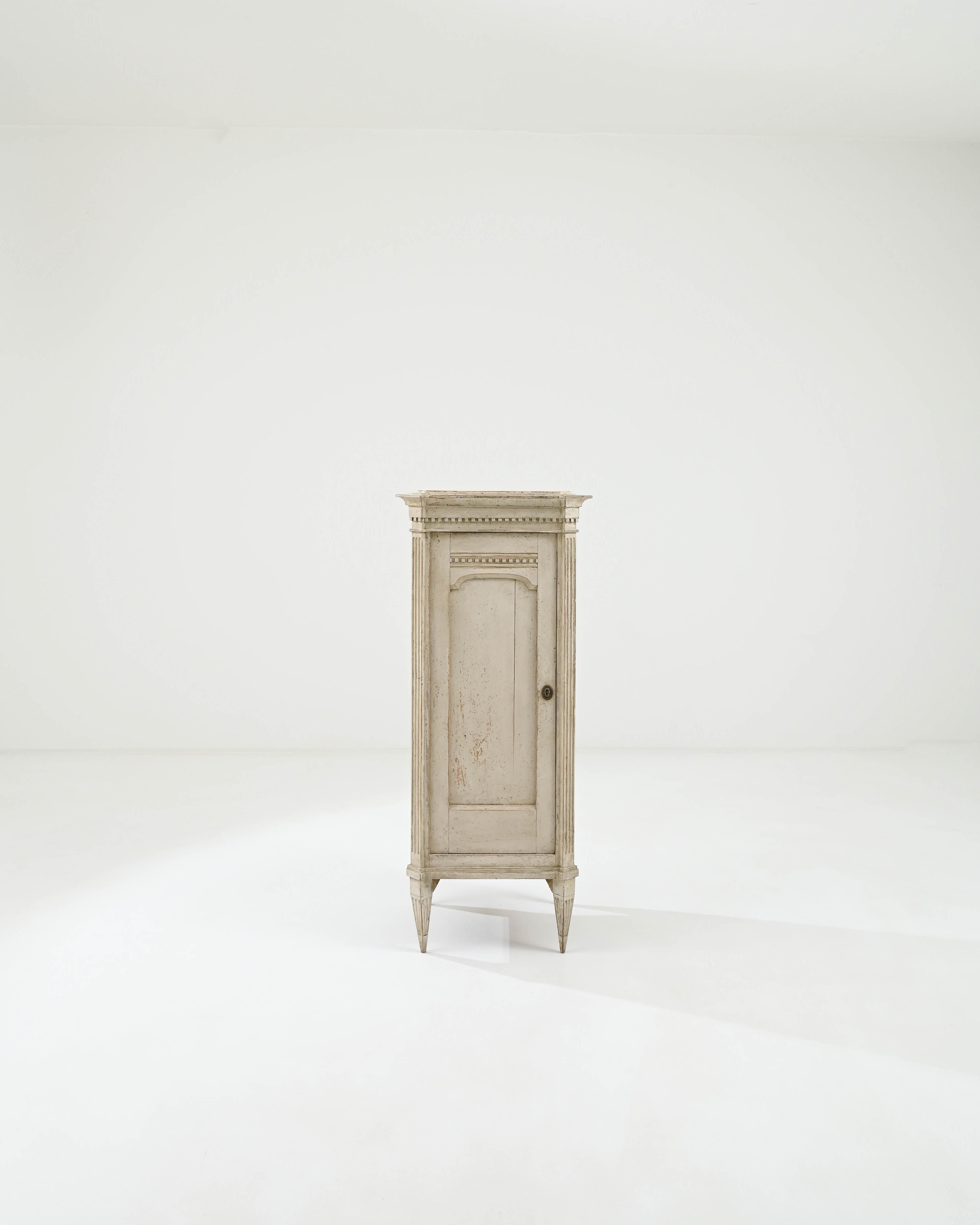 This vintage wooden cabinet embodies the subdued elegance of Gustavian style. Built in Scandinavia at the turn of the century, delicate Neoclassical elements give the case an air of refinement. The slender silhouette is emphasized by fluted columns;