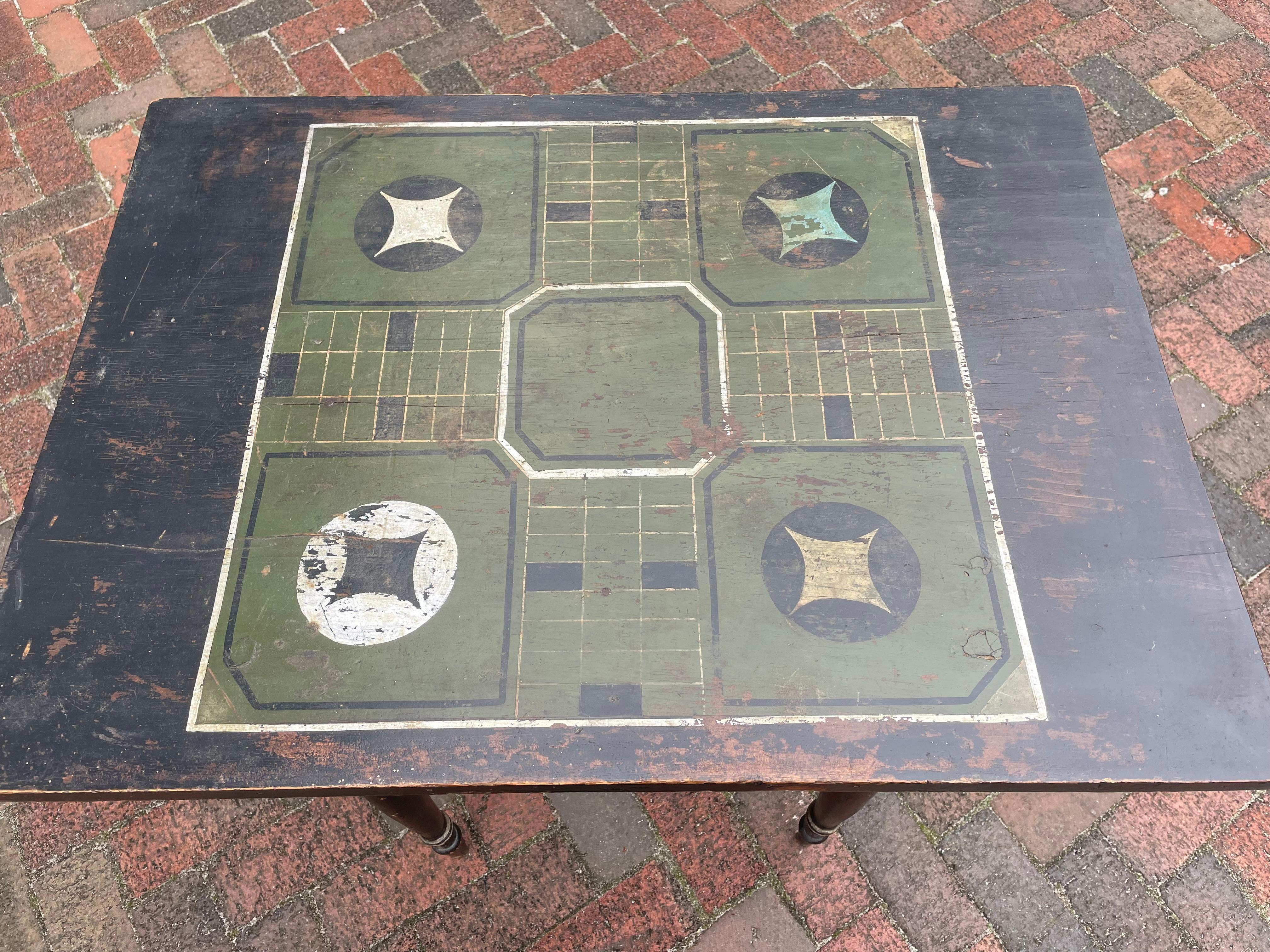 Lovely Turn of the Century Parcheesi Game/Side Table. In all over black paint with green and polychrome painted Parcheesi board pattern on single board top. Base with turned, tapered legs highlighted with gold and silver decorative paint throughout.