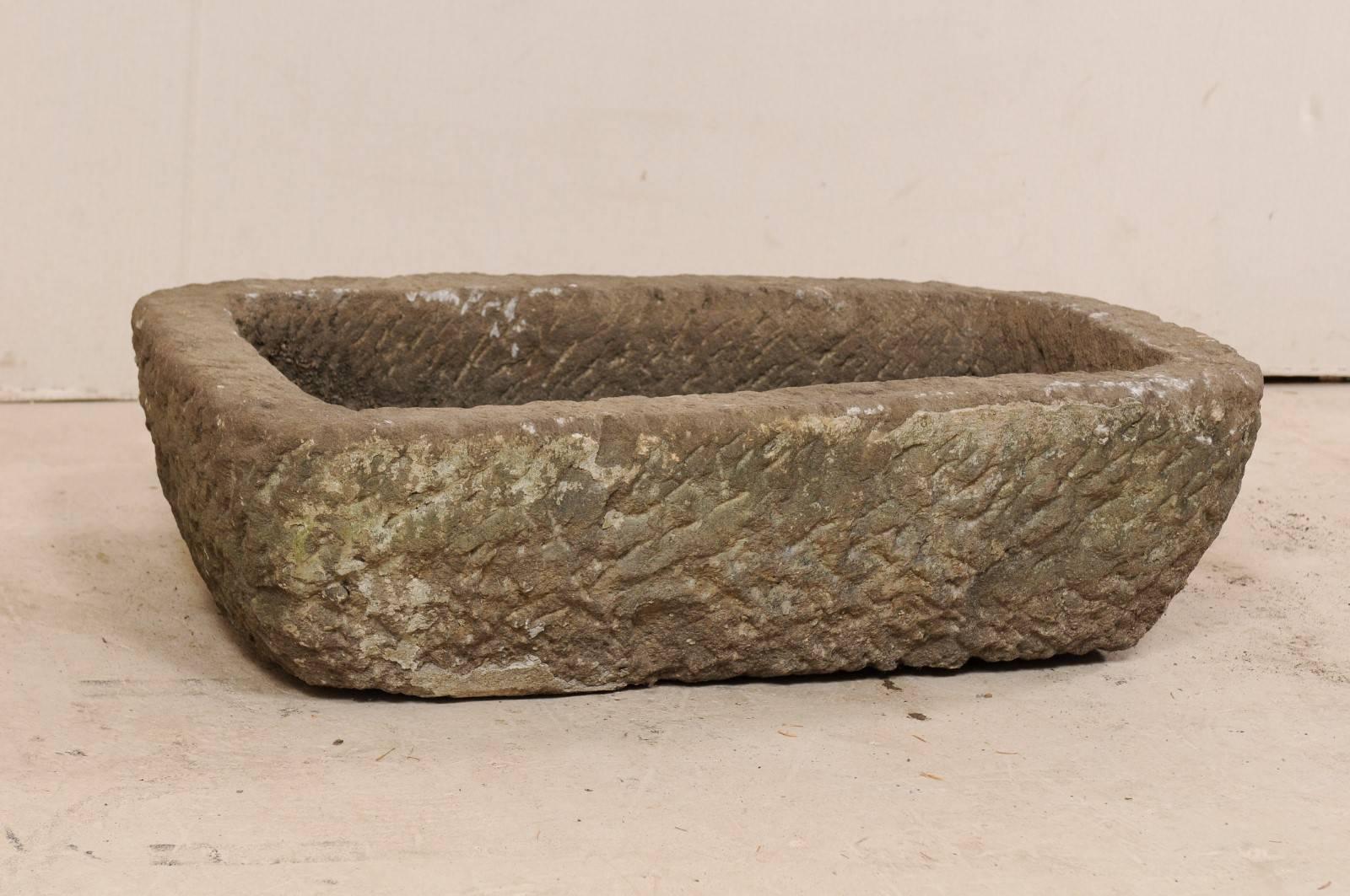A stone trough from the turn of the 19th and 20th century. This antique stone trough from Indonesia is rectangular in shape and has been carved out of a single piece of stone. It is both beautiful and rustic, simplistic in design. A delightful