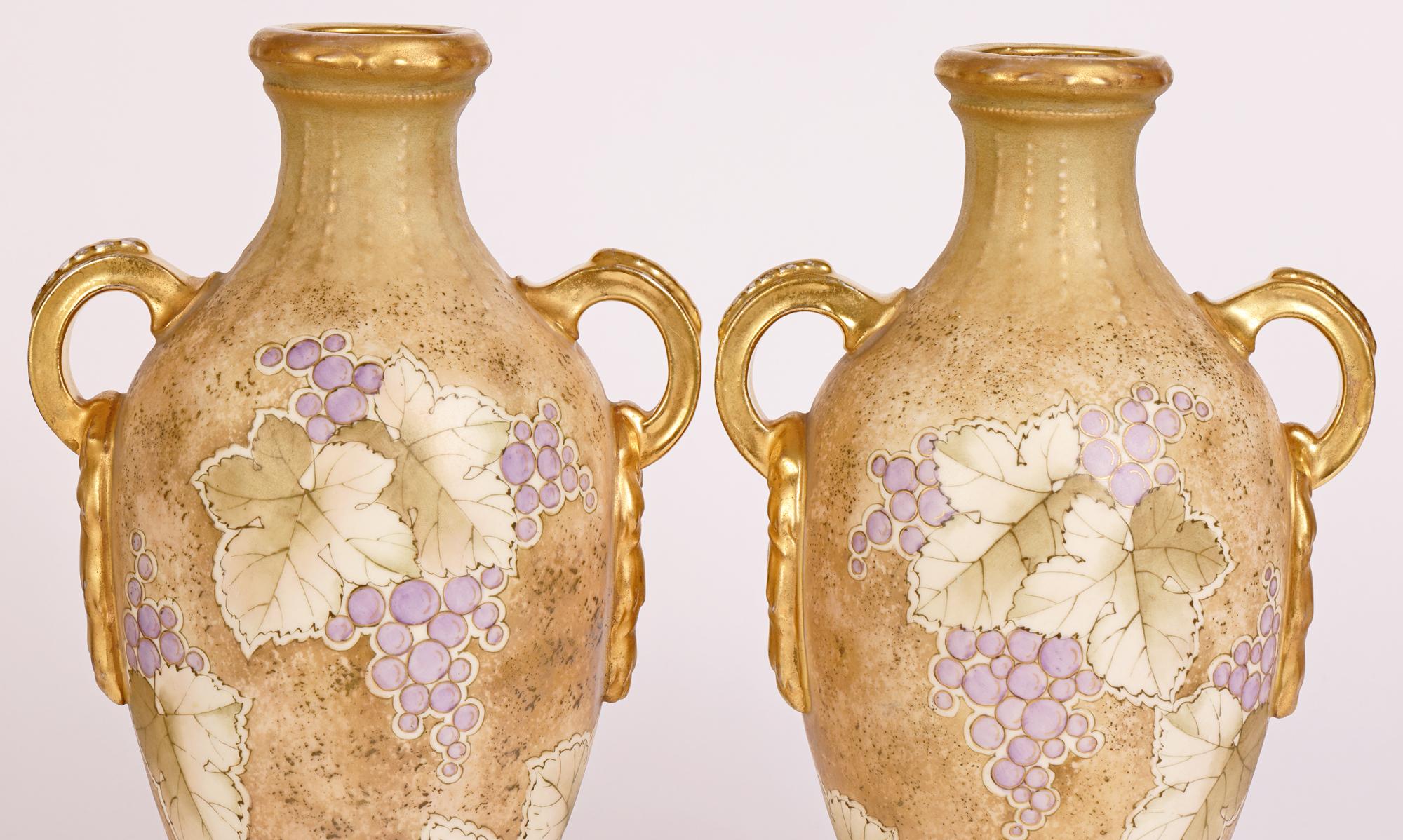 A stylish pair Austrian Art Nouveau hand-painted twin handled vases decorated with fruiting vines by the renowned Turn Teplitz factory run by Riessner, Stellmacher & Kessel and dating from around 1900. The finely made porcelain vases stand on narrow
