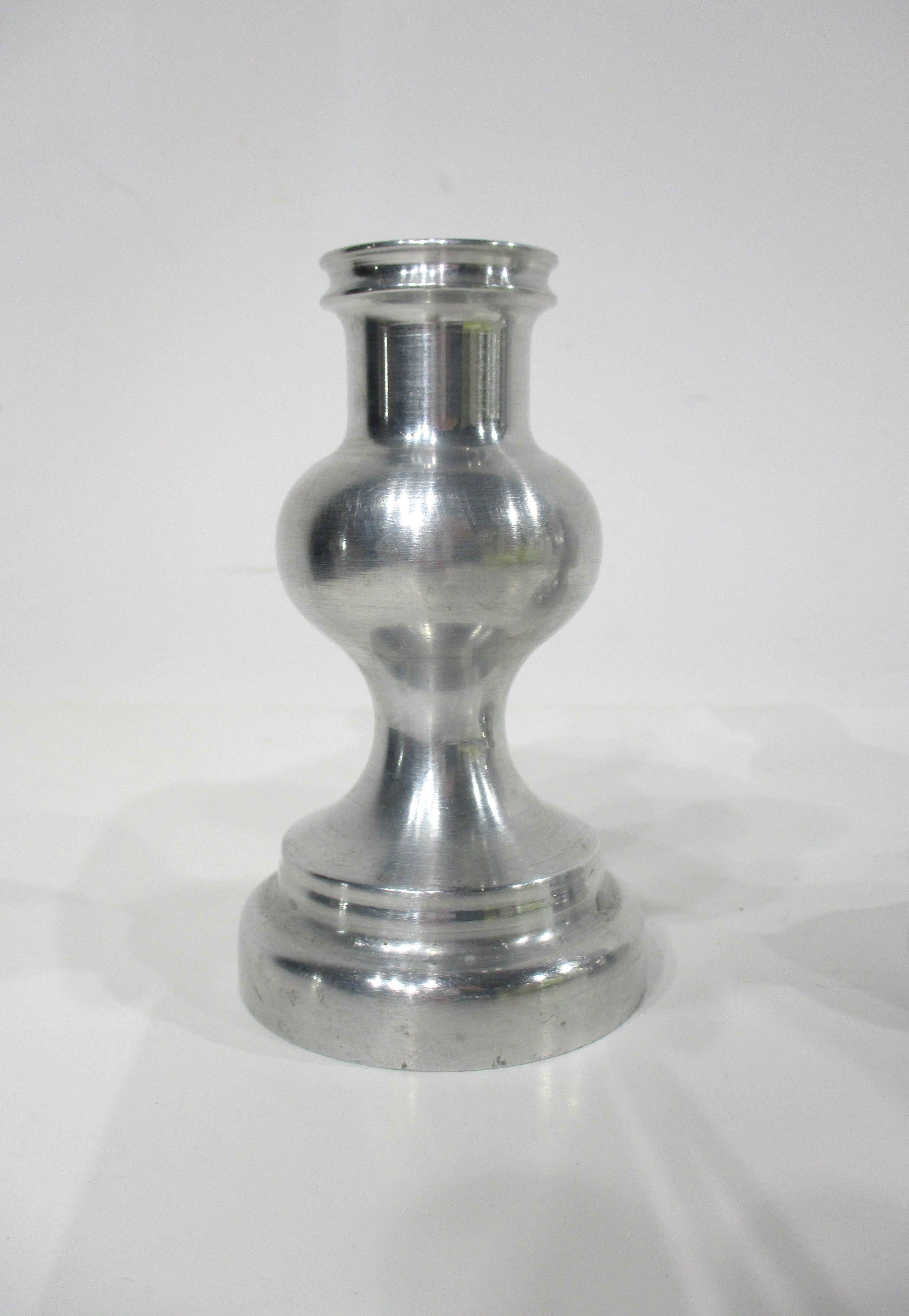 A pair of turned aluminum machine age art deco styled candlestick with nice rounded center having top and bottom details . These would fit into any style of interior from mid century , art deco or where you need some simple form to accent you space