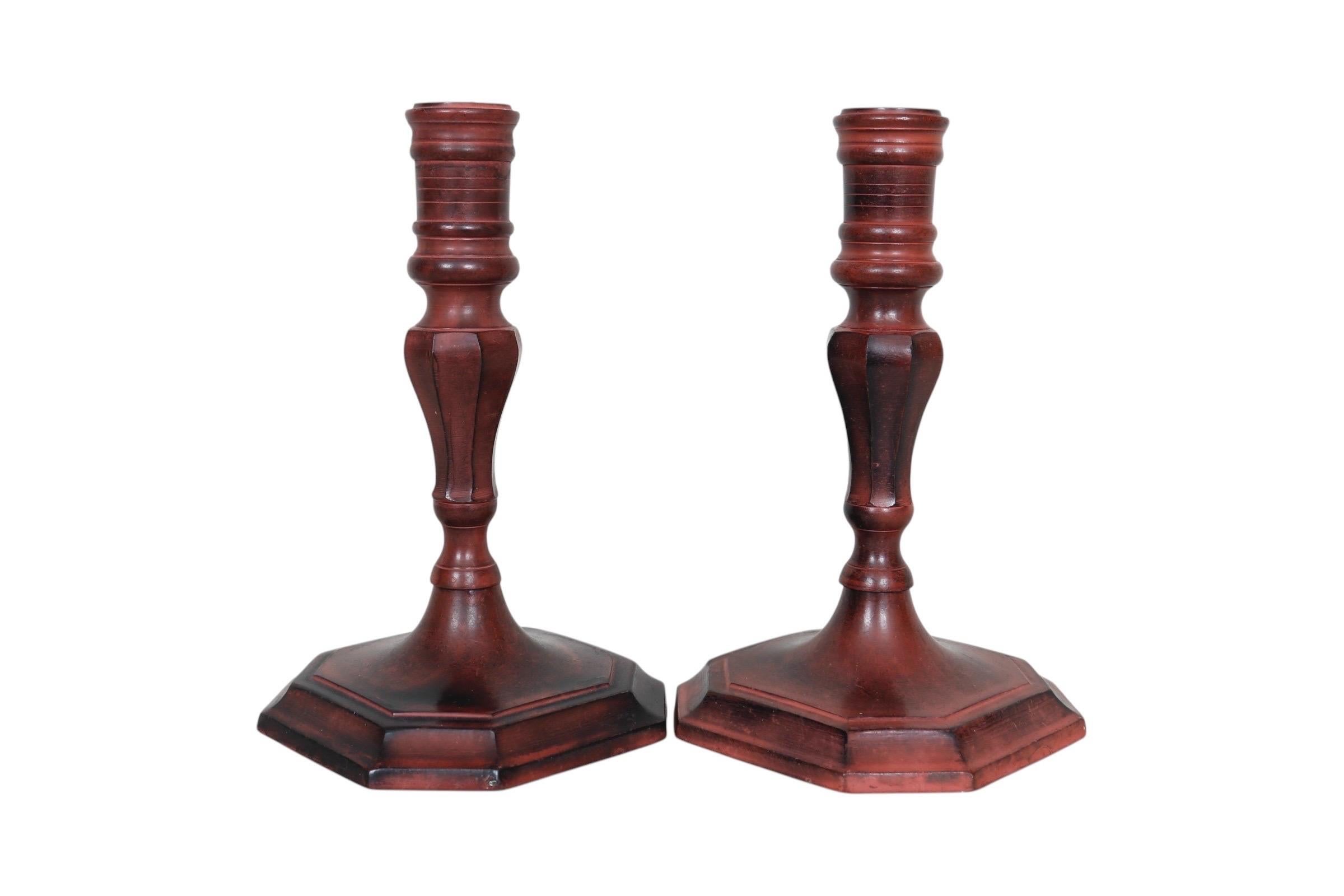 Una coppia di portacandele in ottone. I tradizionali portacandele torniti con base ottagonale sono colorati con una finitura rossa.
