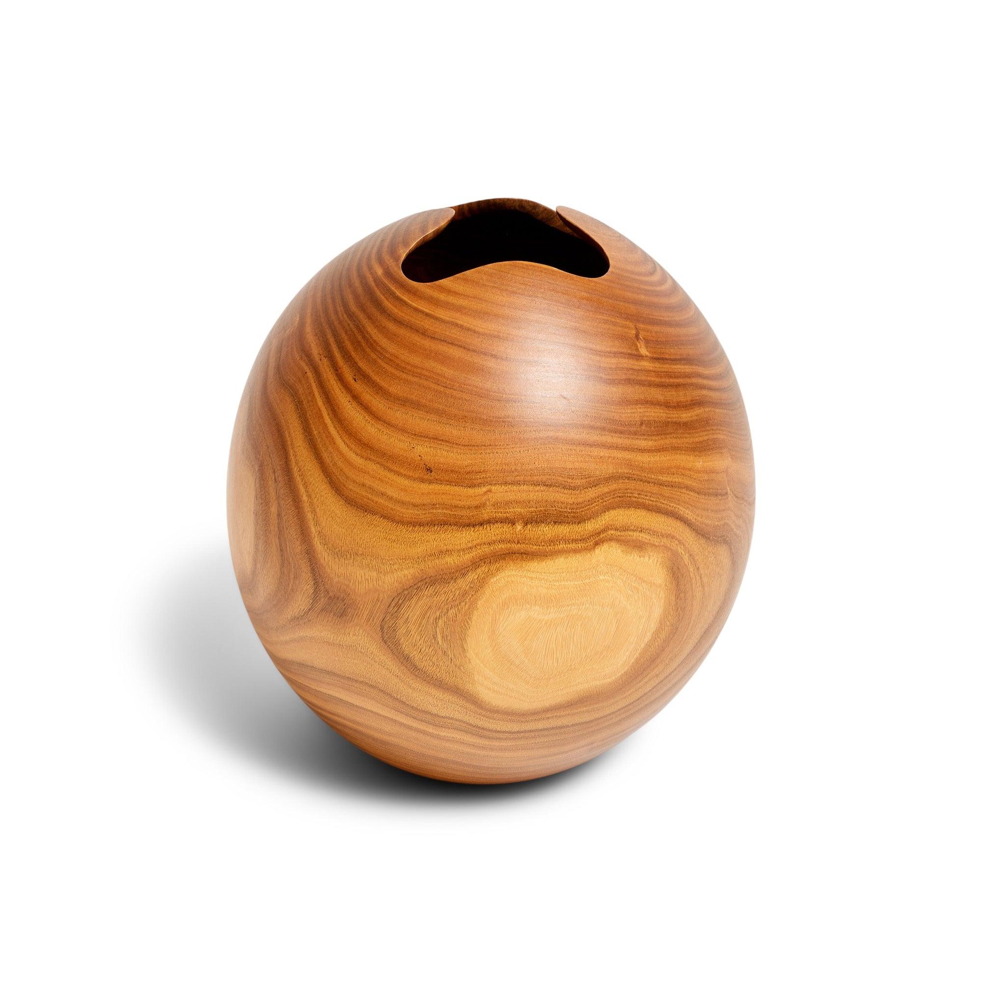 Un vaso sferico dalla grana splendida e magistralmente tornito, ricavato da un unico pezzo di noce di Clao e caratterizzato da un'espressiva apertura a forma libera.