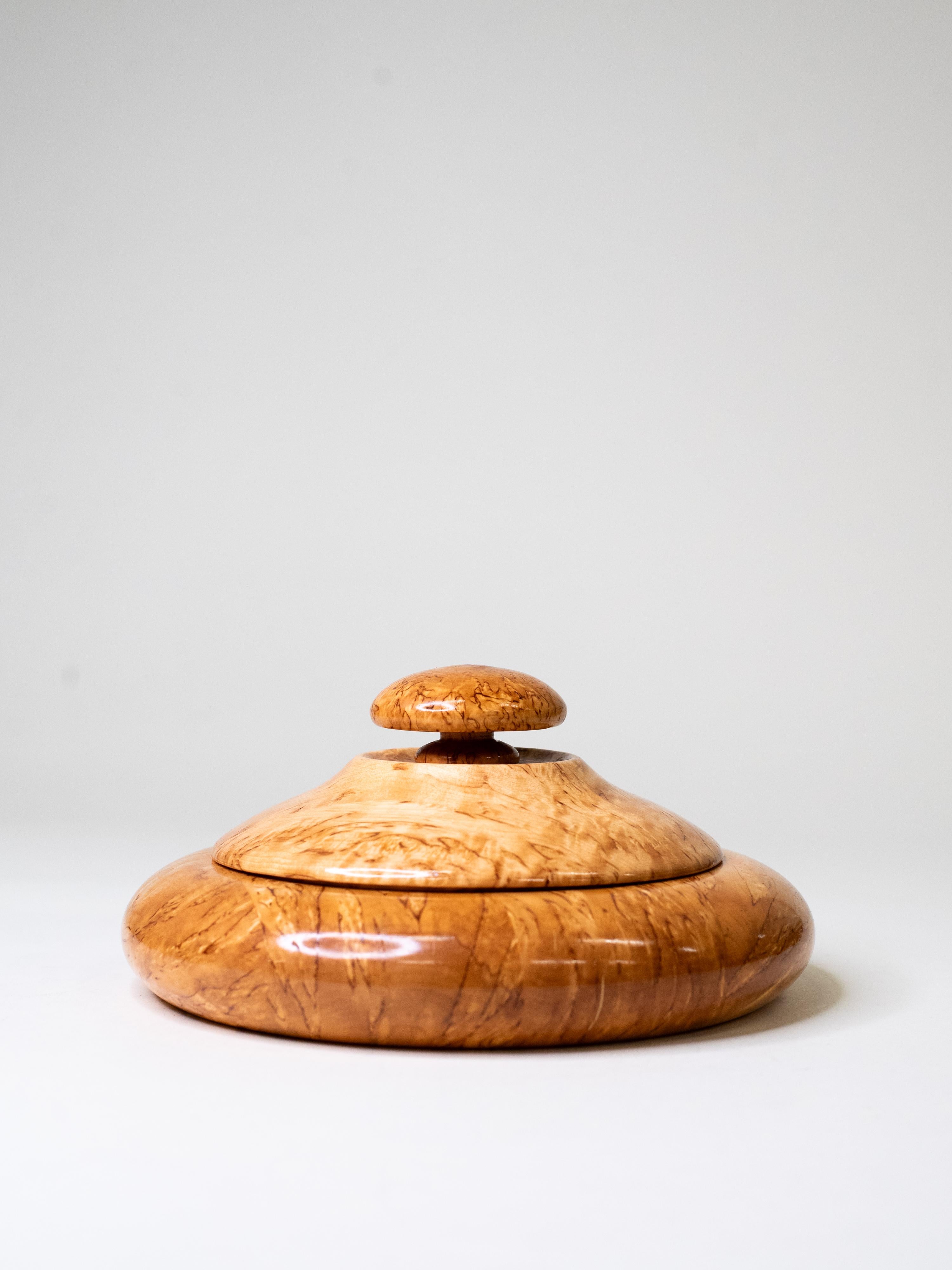 A finely turned lidded bowl in solid curly birch, made in Finland during the 1970s. The sculptural form combines smooth, flowing lines with the intricate natural pattern of visakoivu - a rare, highly figured variety of birch prized in Finnish