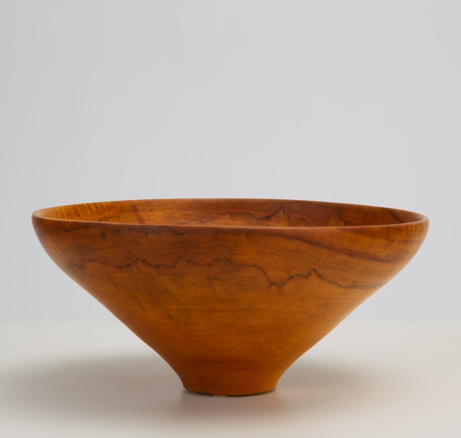 A California made turned wood bowl with a tapered foot and understated figuring in the maple wood. Signed on bottom 