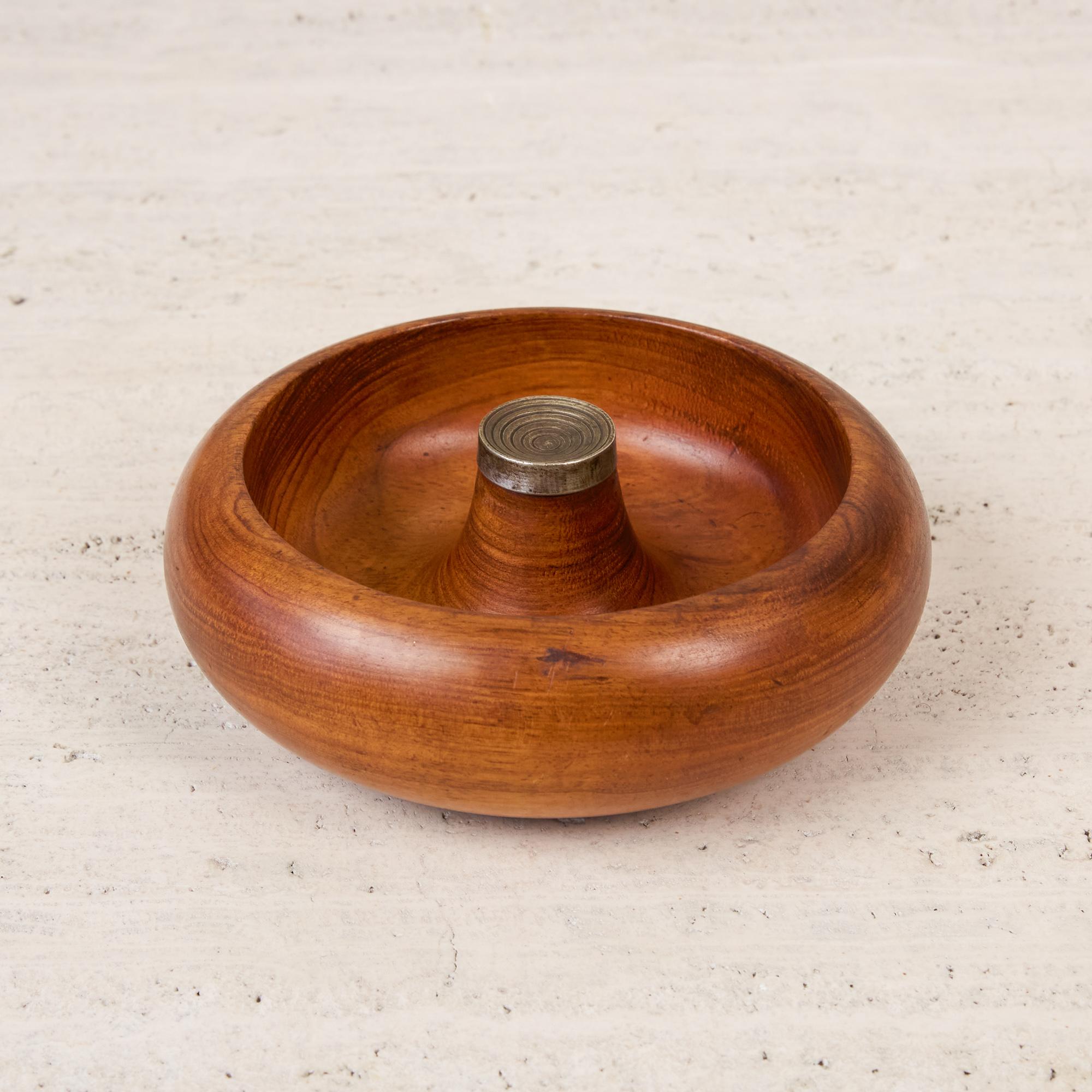 Walnut and brass nut bowl by Pelican of Australia. The bowl features a turned walnut body with brass center piece. The sculpted center section of the bowl forms upward and ends with the patinated brass cap with incensed grooves. These types of bowls