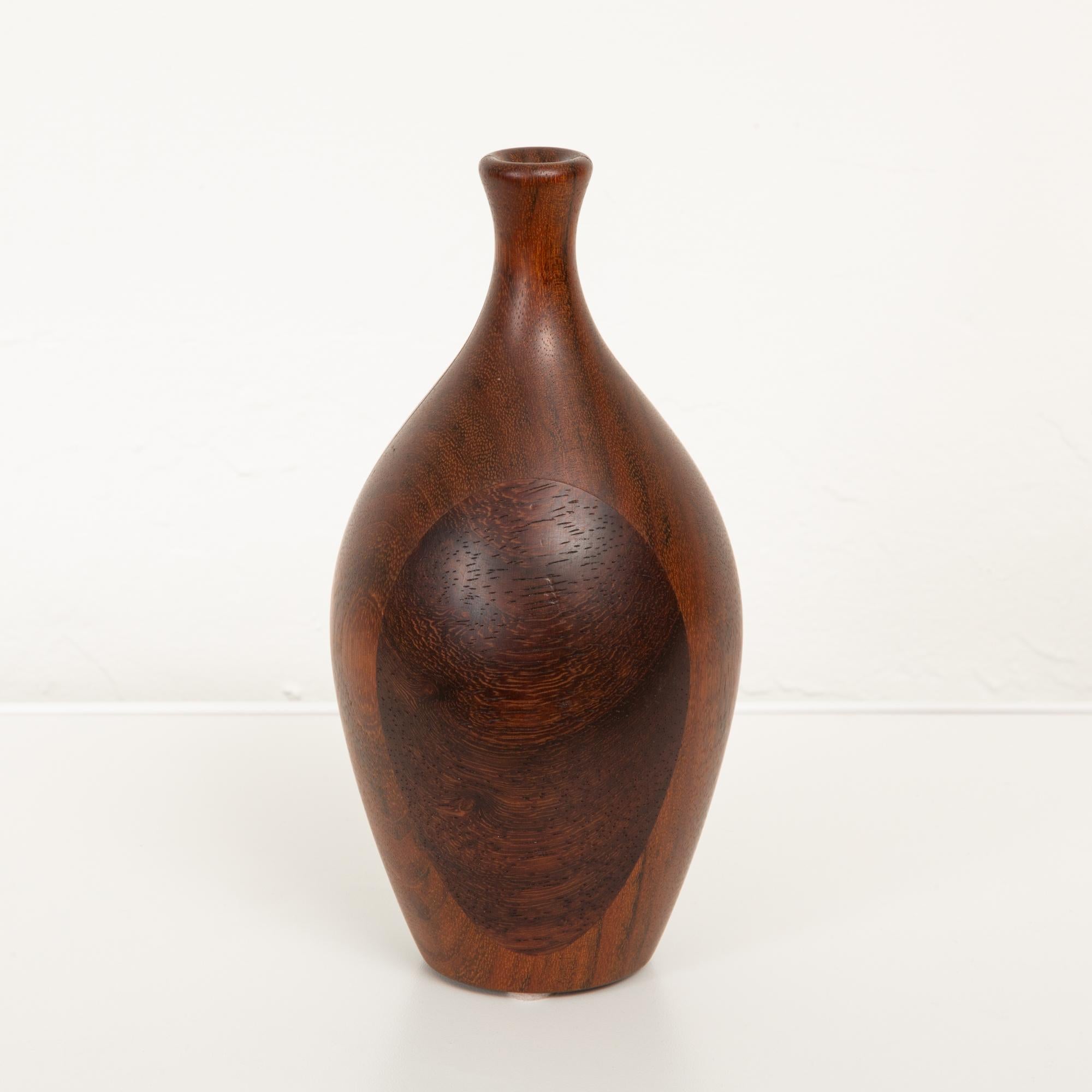 A hand turned wooden vessel featuring a stack laminated body and detailed precision in the execution of the construction. The wood has a beautiful patina that is appropriate for the age of the piece with subtle grain pattern and some darker