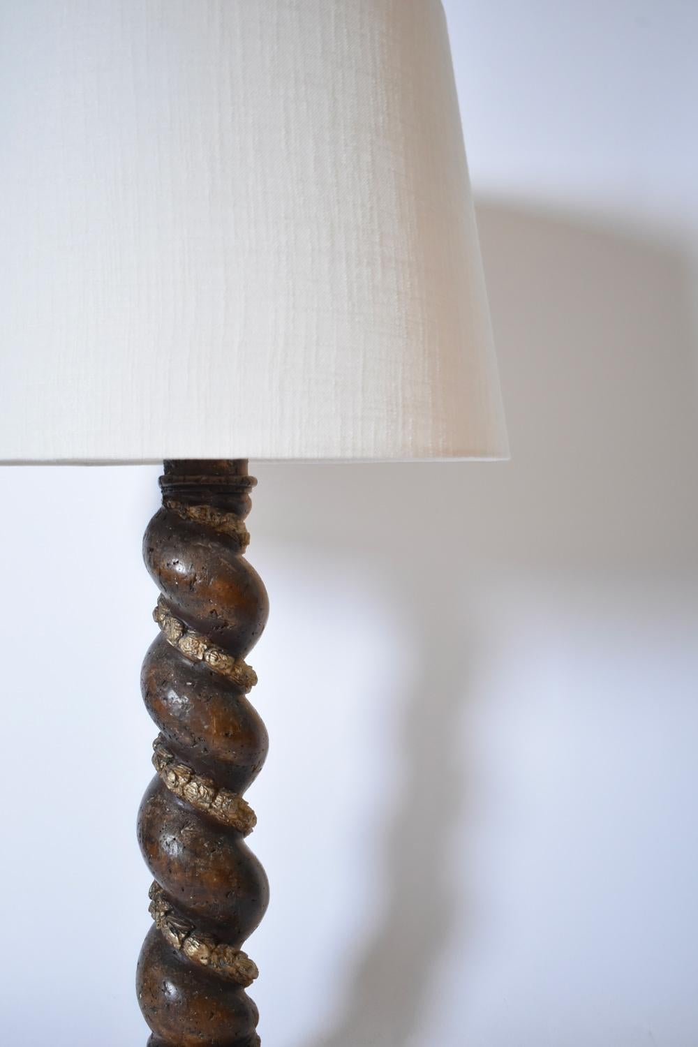 Lampada da tavolo in legno tornito con decorazione floreale e fregio in alloro dorato che rappresenta una colonna su una base quadrata. Italia, XIX secolo.