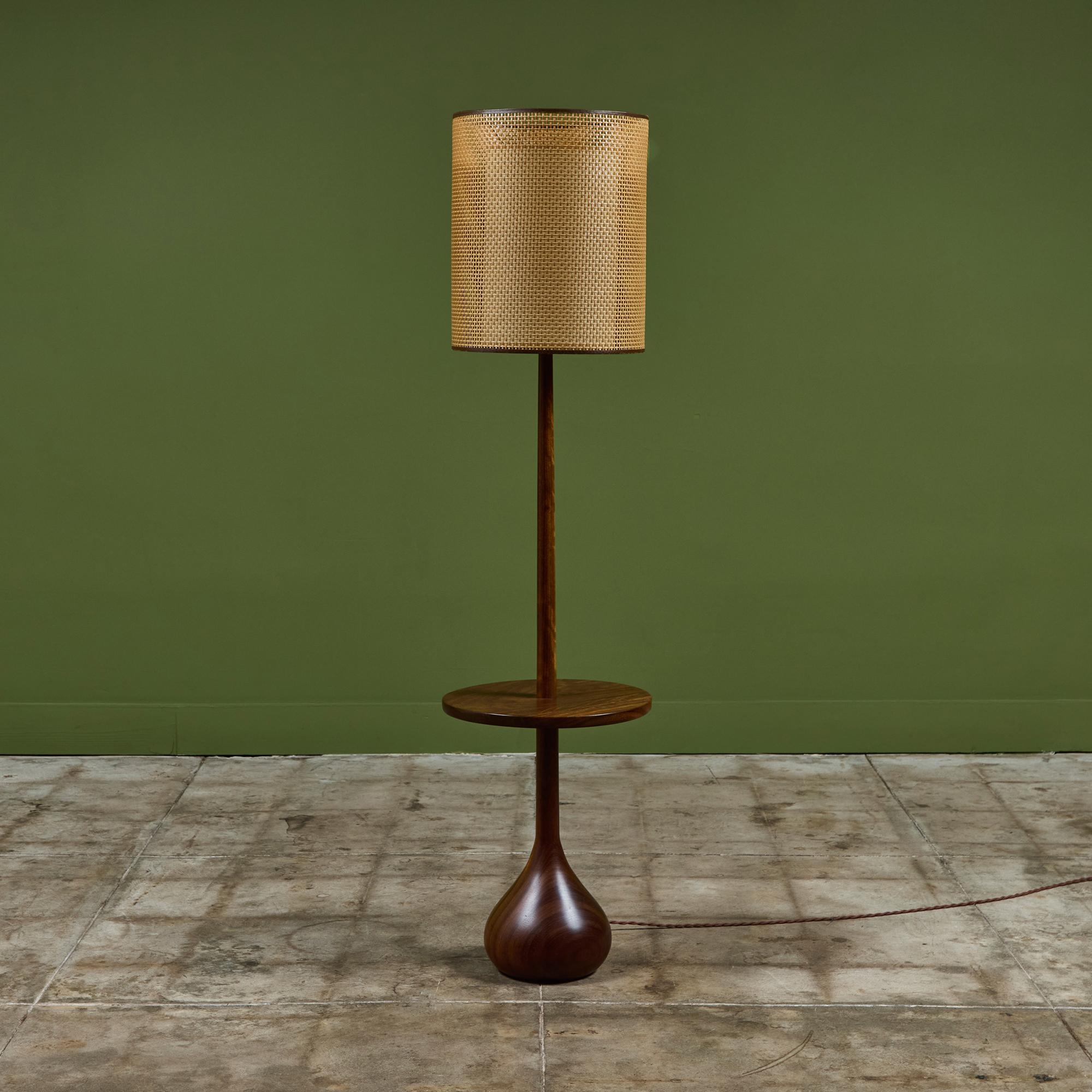 Tournée en bois d'Afromosia, cette lampe bulbeuse a une base ronde organique douce et large, qui se rétrécit en un cou mince vers le haut où se trouve un abat-jour en rotin. La lampe comprend également une table d'appoint ronde de