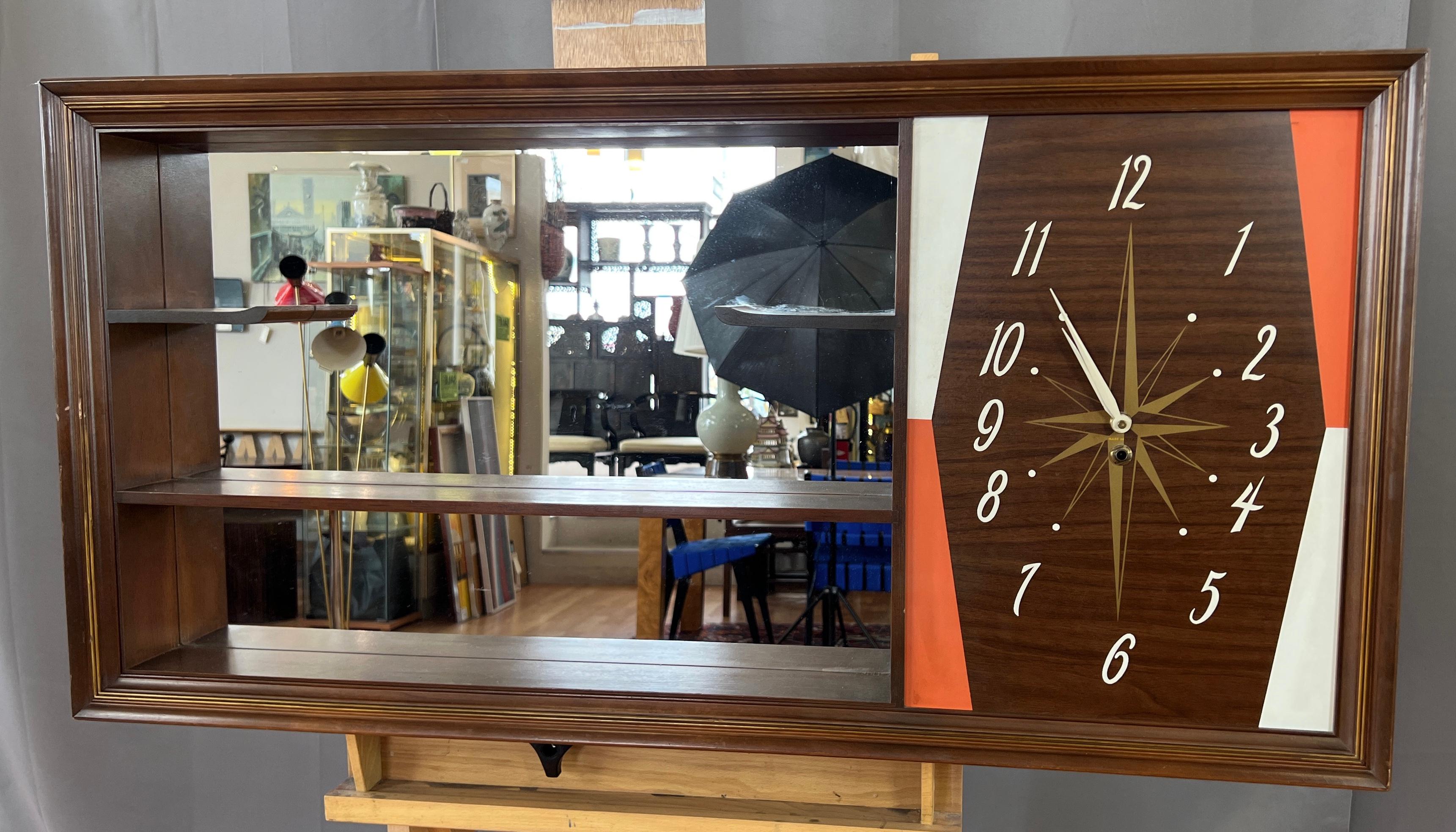 A very handsome 1960s walnut wall mounted curio shelf (or open-faced shadow box) with mirrored interior and integrated clock by Turner Manufacturing Company.

Large, eye-catching clock has a great mid-century aesthetic, with orange and white