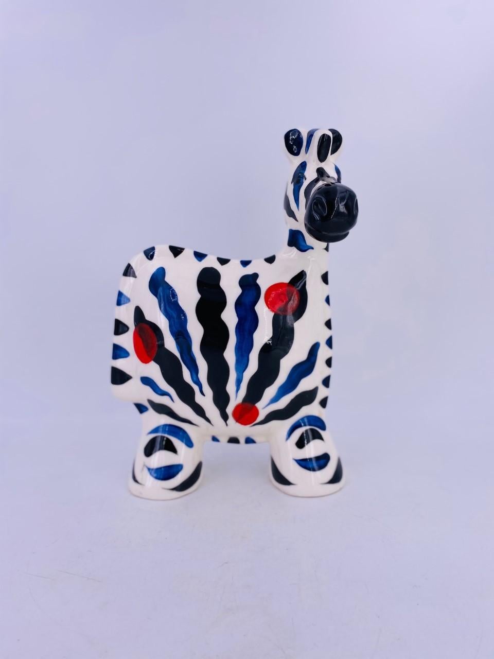 Beautifully crafted Turov Arts of Russia ceramic zebra figure. The figure presents the form in an array of black, blue stripes over a white glaze with red dots intermittent on the figure. Colorful and whimsical. This is a piece that adds color and