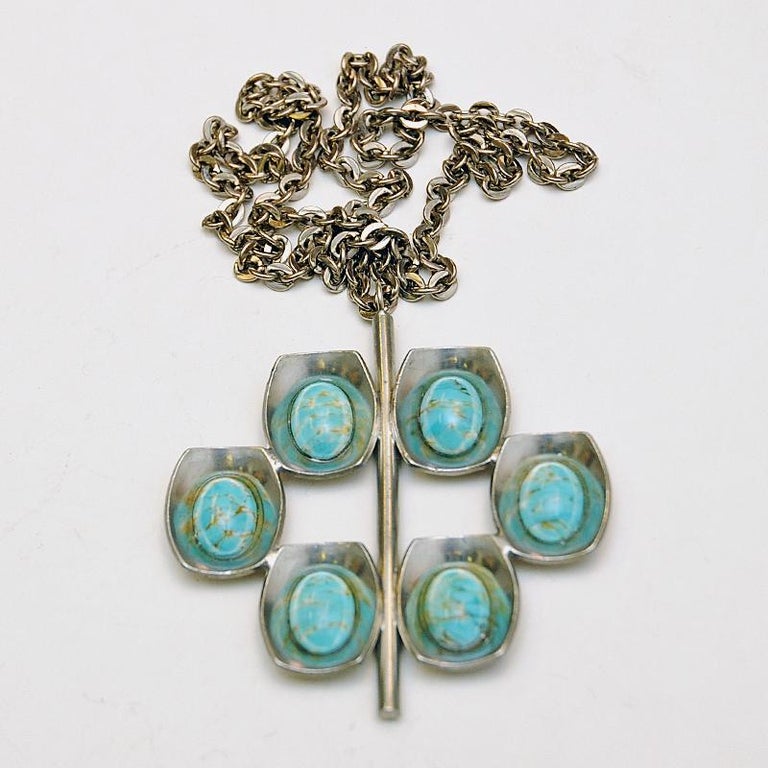 Beautiful turqious blue stone pewter necklace by Jørgen Jensen, Danmark 1950s.
The pendant has six eggshaped stones with crackeled copper colored details inside the stones. Each stone is surrounded by a bowl of pewter connected to a stom in the