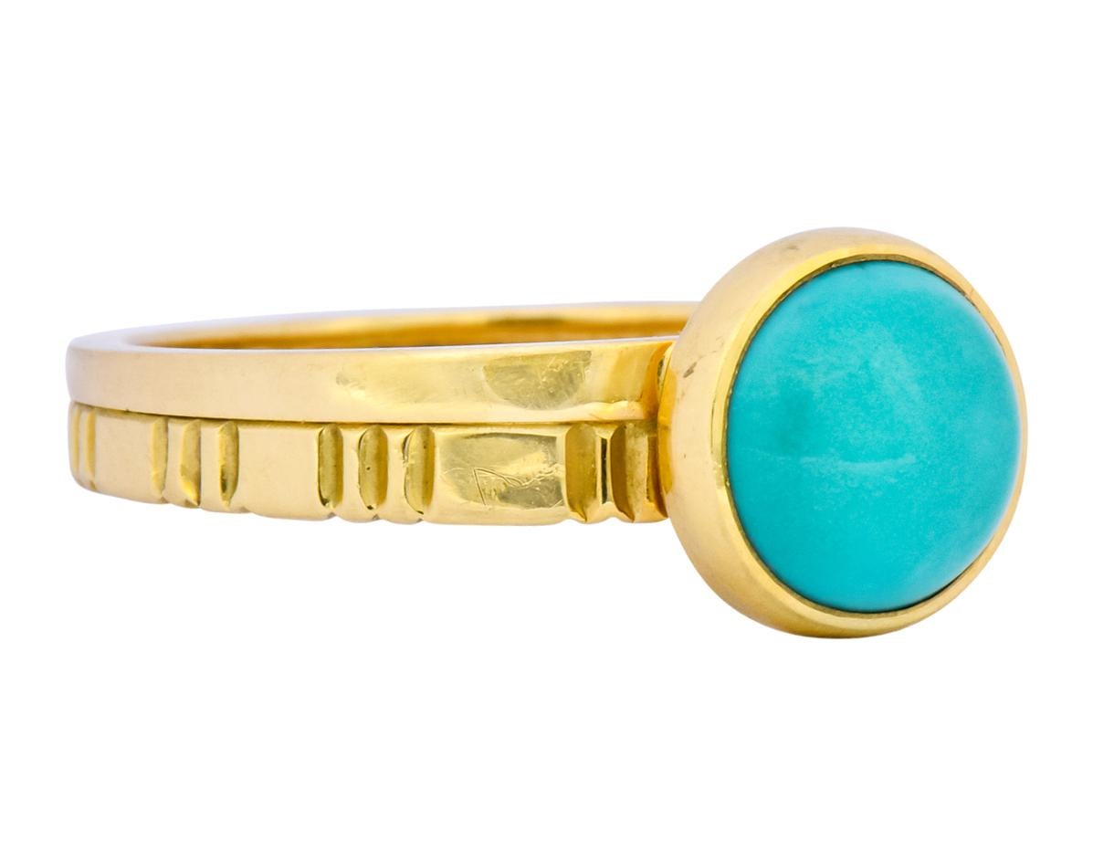 Centering a turquoise cabochon measuring approximately 3/8 inch, opaque and slightly greenish-blue with no matrix

Bezel set in a polished gold surround

Completed by a deeply ridged and conjoined polished gold shank

With makers mark and stamped