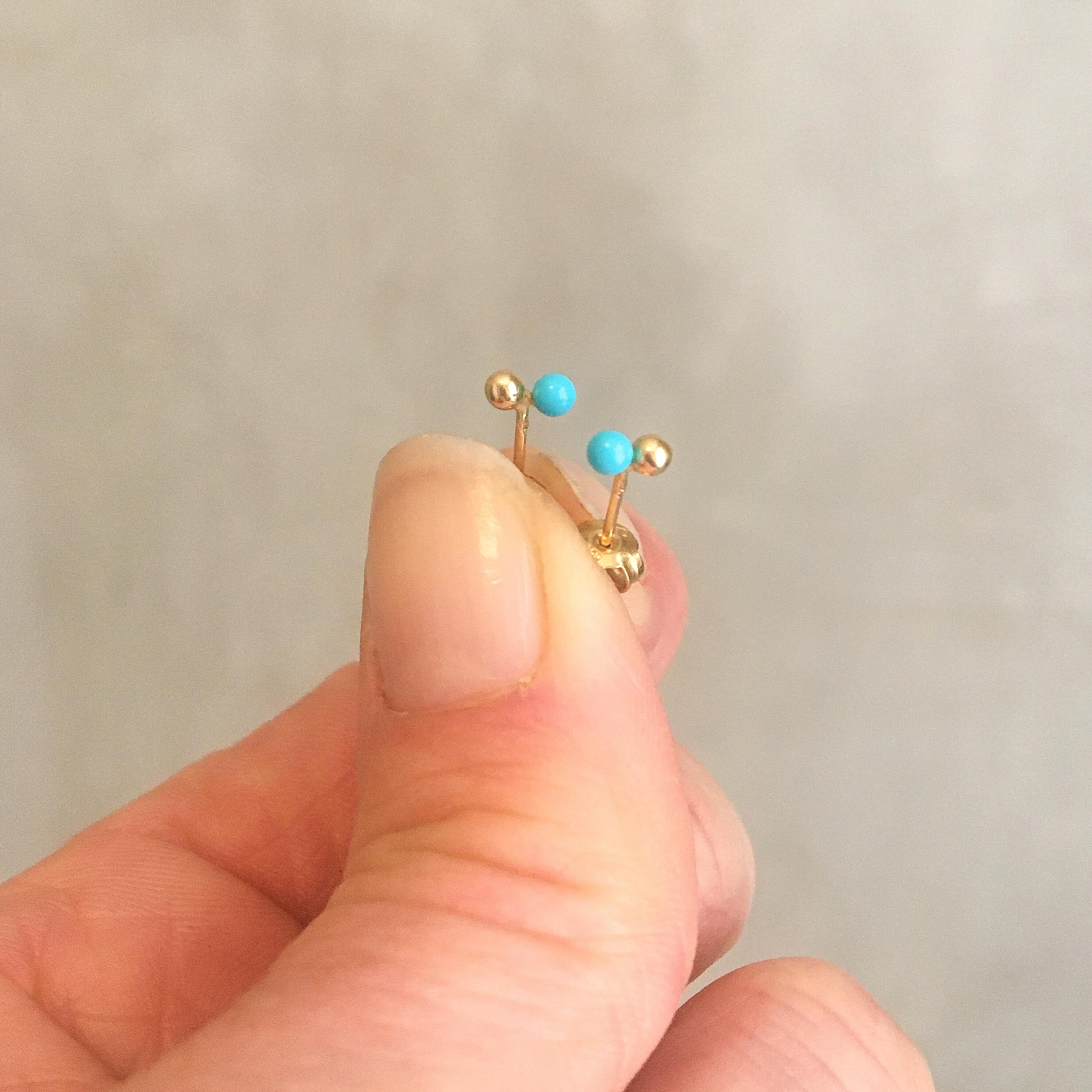 These lovely vintage mid-century turquoise stud earrings are created in 18 karat yellow gold. The earrings feature two small round balls, one in turquoise and the other in gold. Turquoise is an opaque stone and is rare and valuable in finer grades