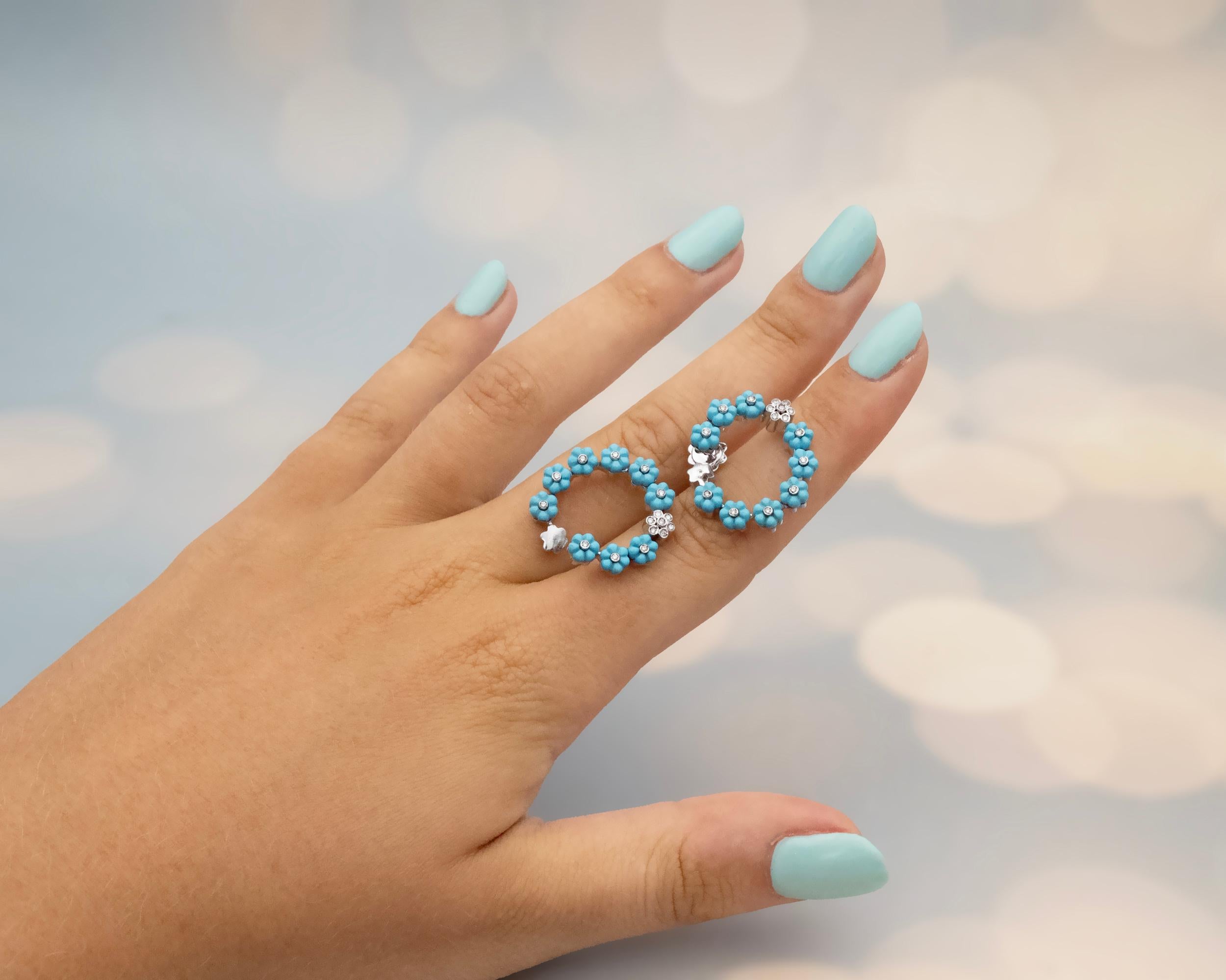 Ces charmantes boucles d'oreilles en or blanc 18 carats présentent un arrangement circulaire de motifs de fleurs de turquoise gravés, chacun centré par un diamant taillé en brillant. À la base de chaque anneau, une grappe contrastante de diamants