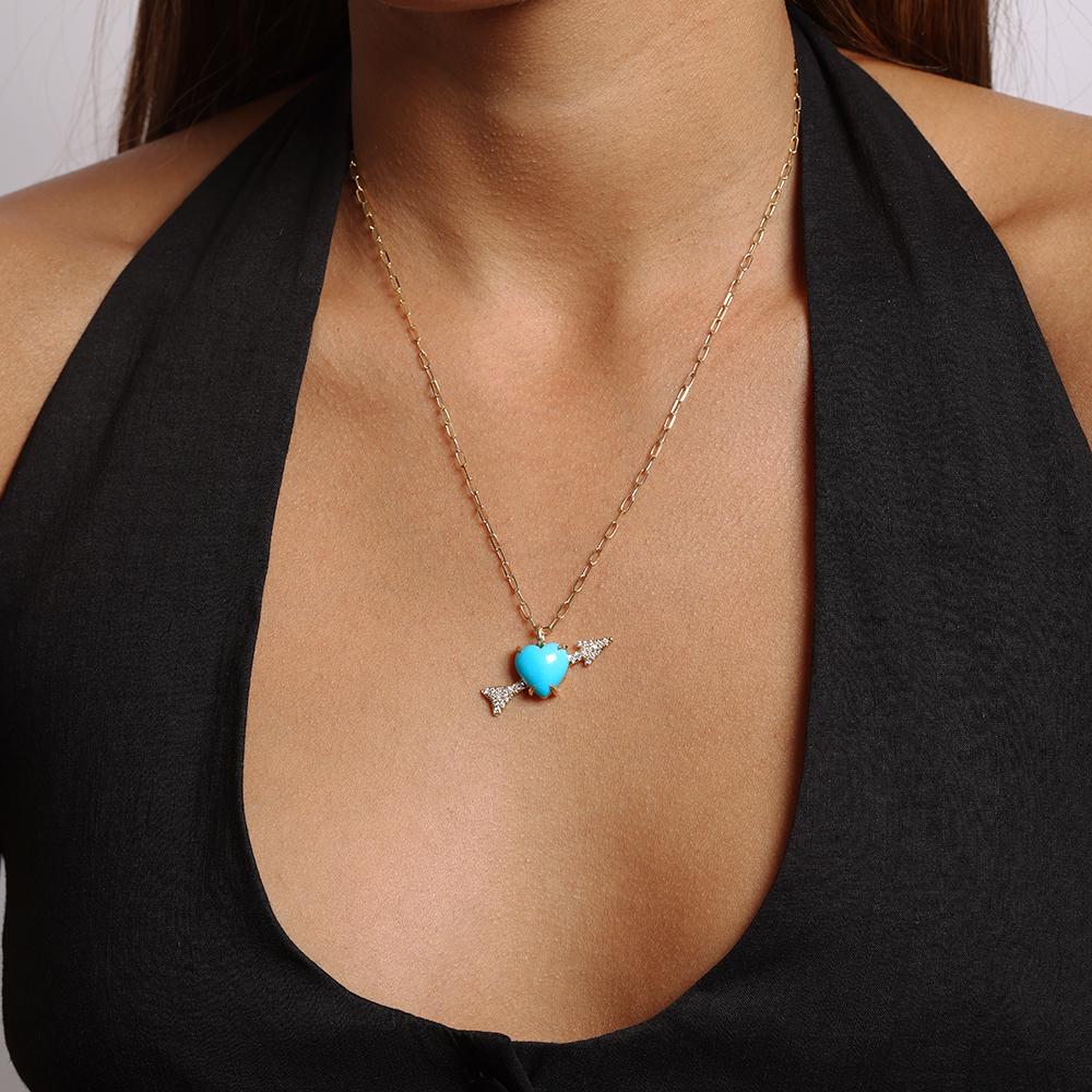 This necklace is crafted in 18kt yellow gold and features a 5.70 ct. heart shaped non-stabilized natural turquoise from the Sleeping Beauty Mine in Arizona. The heart and arrow design dangles from an 18