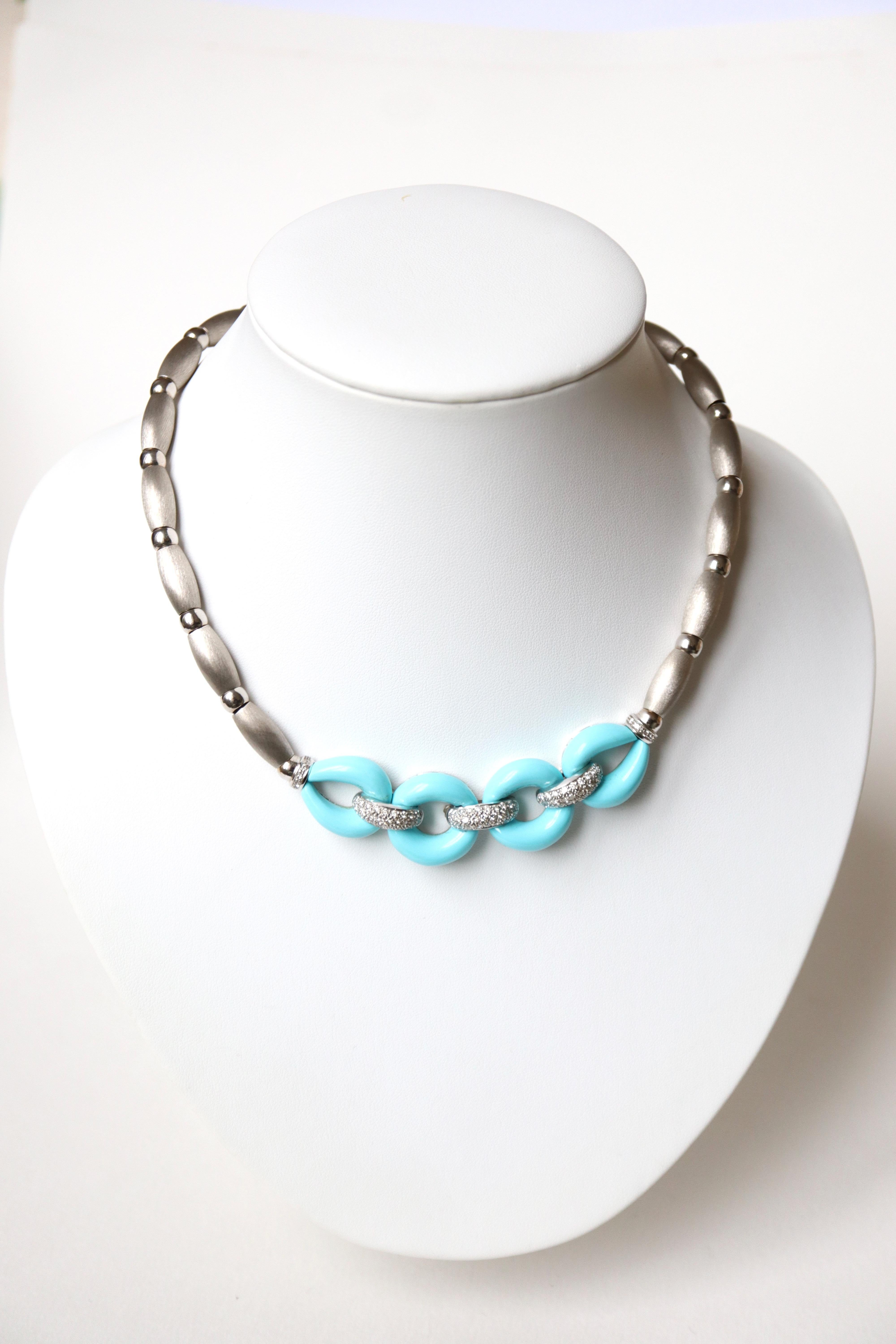Turquoise and diamond brushed 18 kt white gold necklace. It is composed of an 18 kt white gold chain threading alternating balls of curved tubes in brushed white gold retaining in its center two circles and two oval patterns of turquoises held