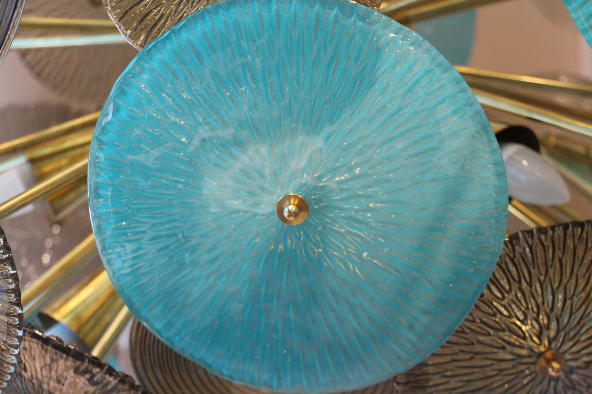 This spectacular chandelier features blue and smoked Murano glass disks. There are several sizes of disks and different patterns. They all have golden glitters inclusions.
Italian custom made chandelier. Brass structure composed of a brass sphere