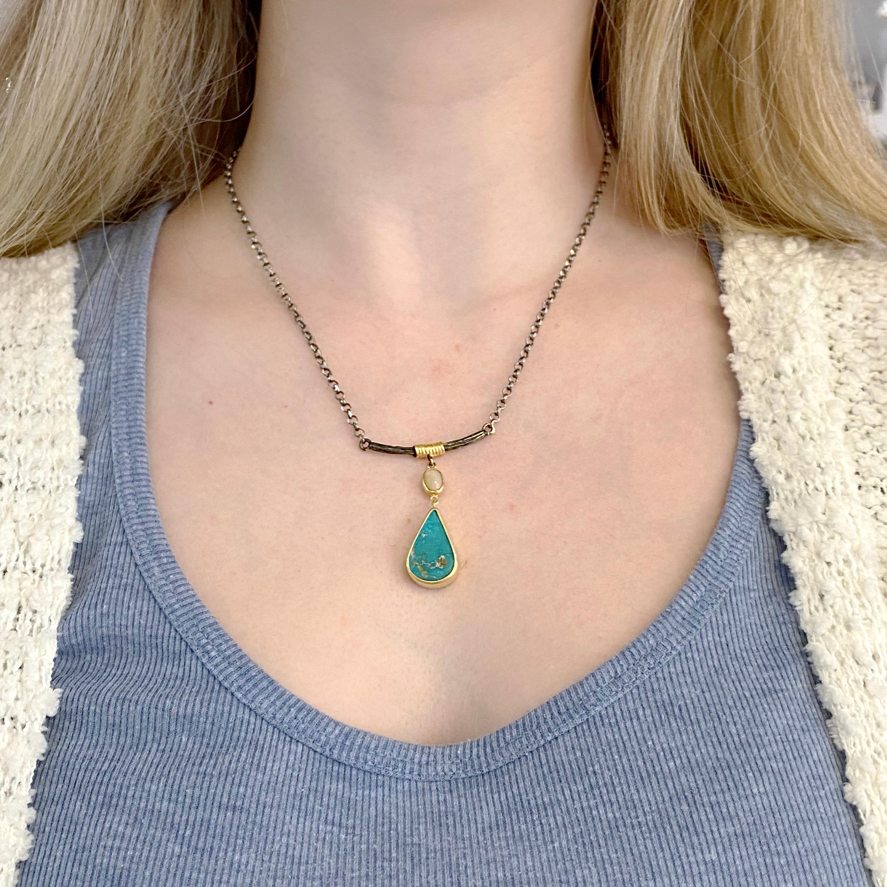 This hand forged pendant is gorgeous with a bezel set opal and turquoise. The opal’s origin is Australia and the turquoise is from New Mexico.  There is a bezel around each gemstone and a very organic design that uses wrapped gold.  The chain is a