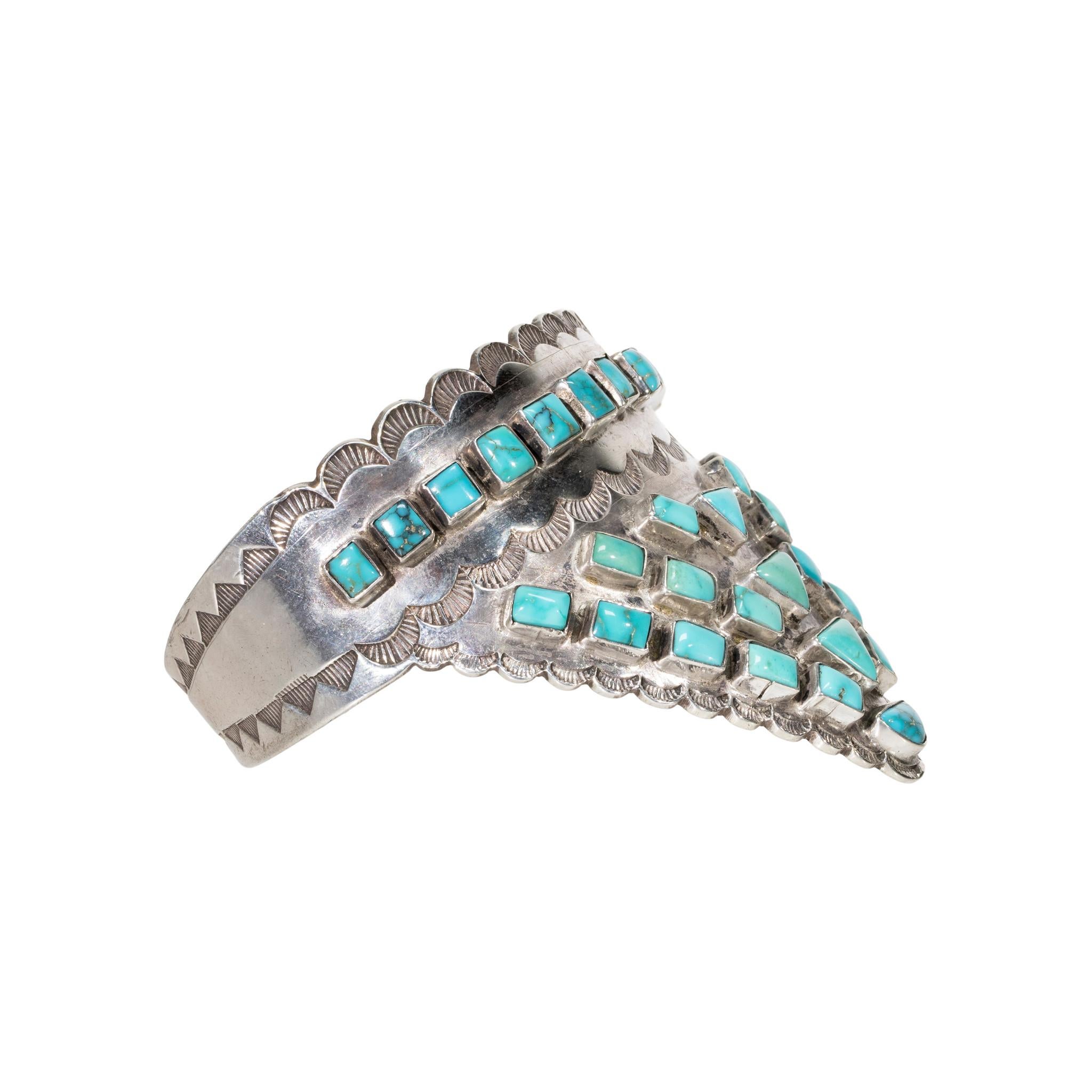 Bracciale in turchese Morenci e argento sterling con oltre 24 pietre di turchese triangolari e quadrate. Le pietre sono incastonate in un robusto scudo d'argento con palmette stampate a mano e bordi smerlati. Le pietre hanno una bella colorazione