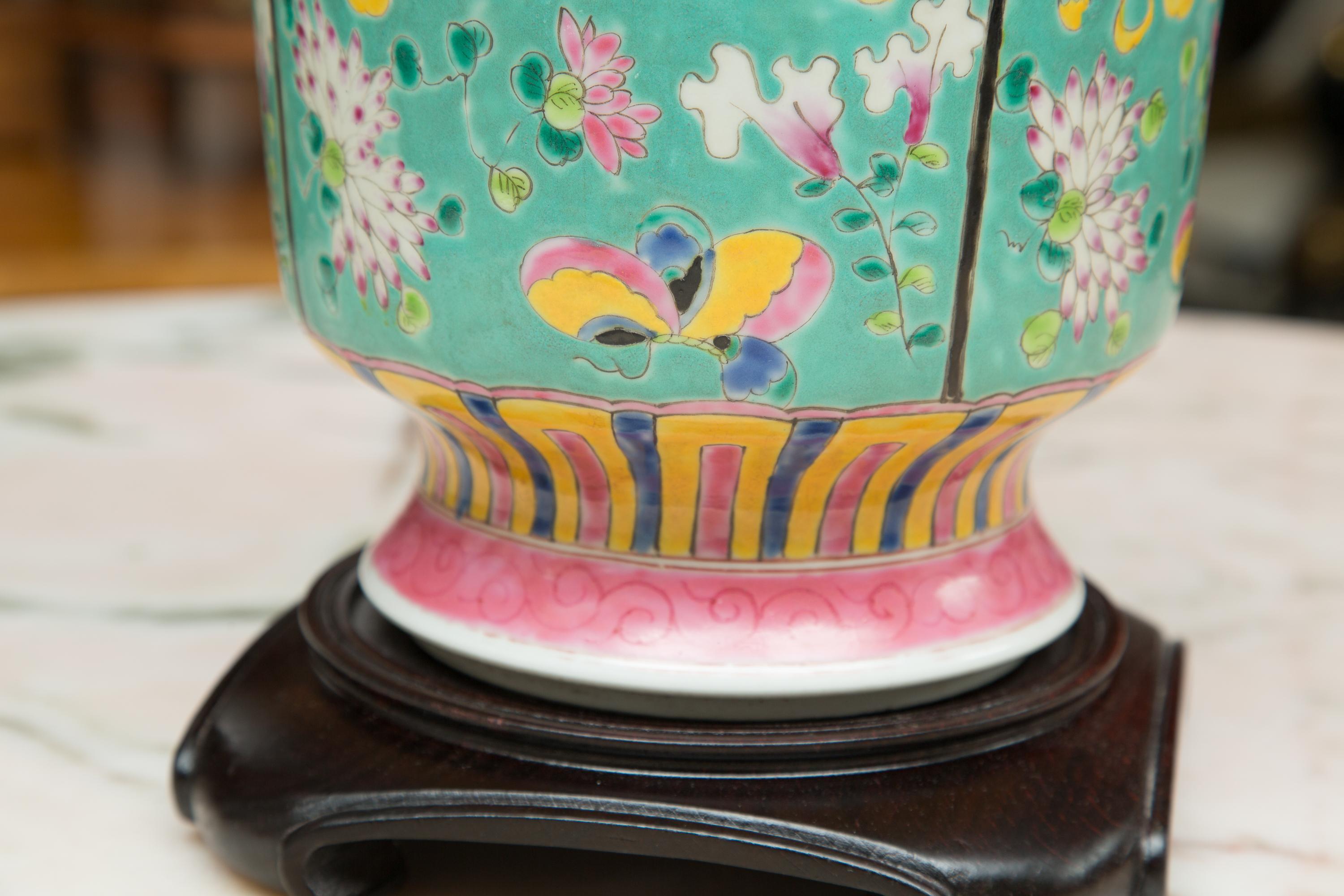 Beautifully hand painted vase with a turquoise background artfully decorated flowers and butterflies'.
