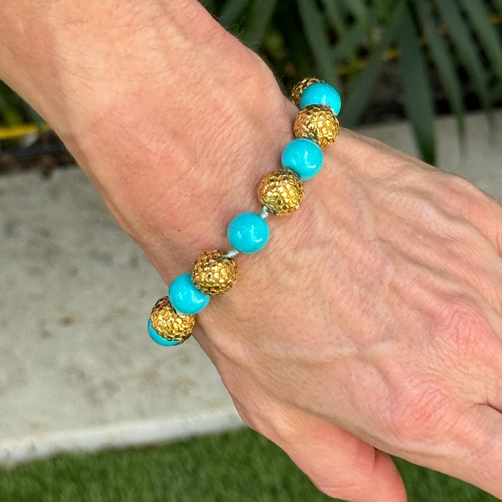 The Turquoise Bead 18 Karat Yellow Gold Ball Bracelet is a captivating piece of jewelry that combines vibrant color with luxurious design. Featuring vivid 10.5mm turquoise beads, this bracelet is adorned with textured gold balls crafted from 18