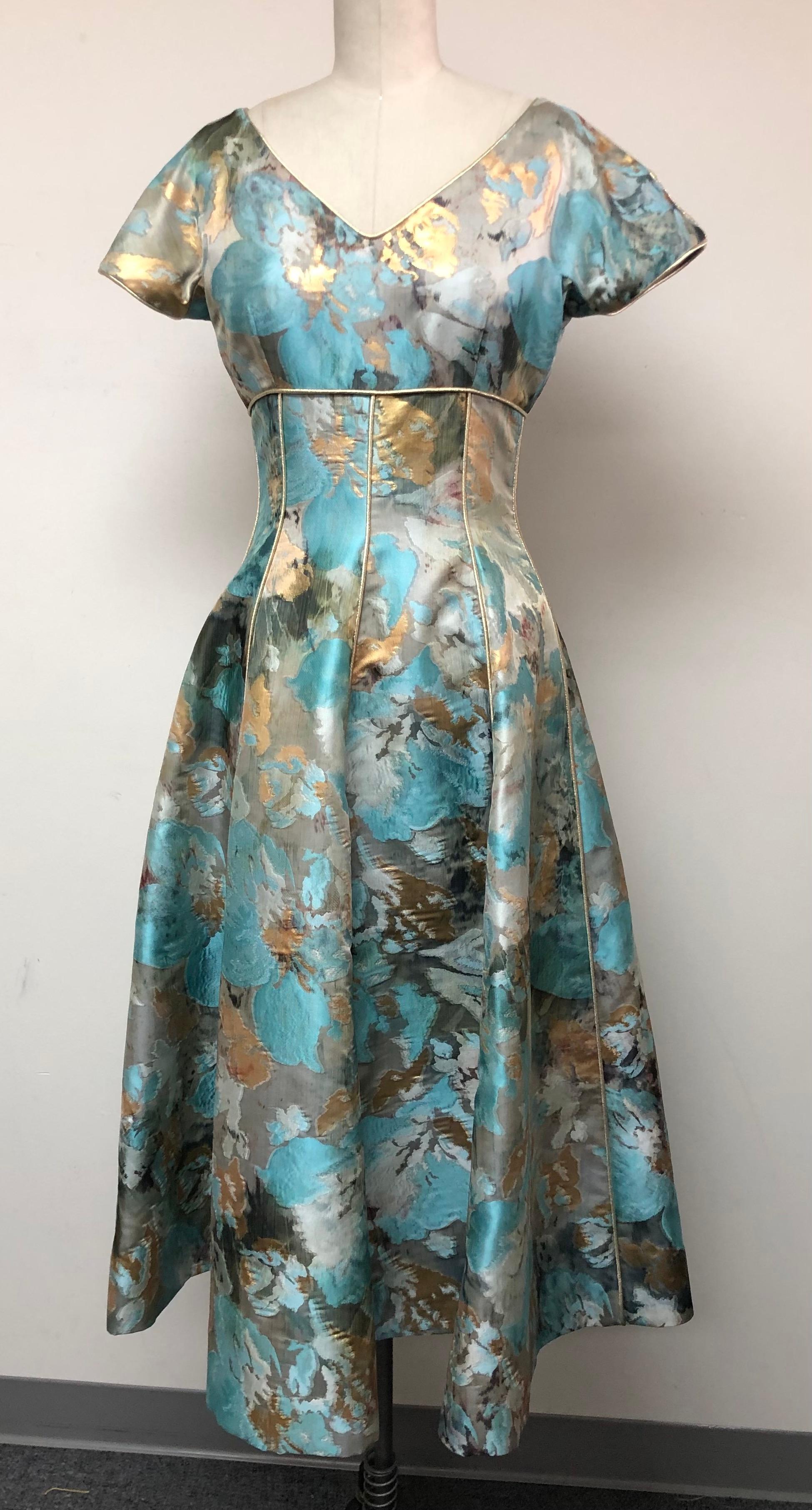 V Neck Fit and Flare Dress in Abstract French Taffeta -Turquoise Black and Gold.  
Piped in Gold throughout for shimmery delight.
The skirt has a lovely fullness adding to its glamour. Great for dancing and making an eye turning entrance. Cocktail