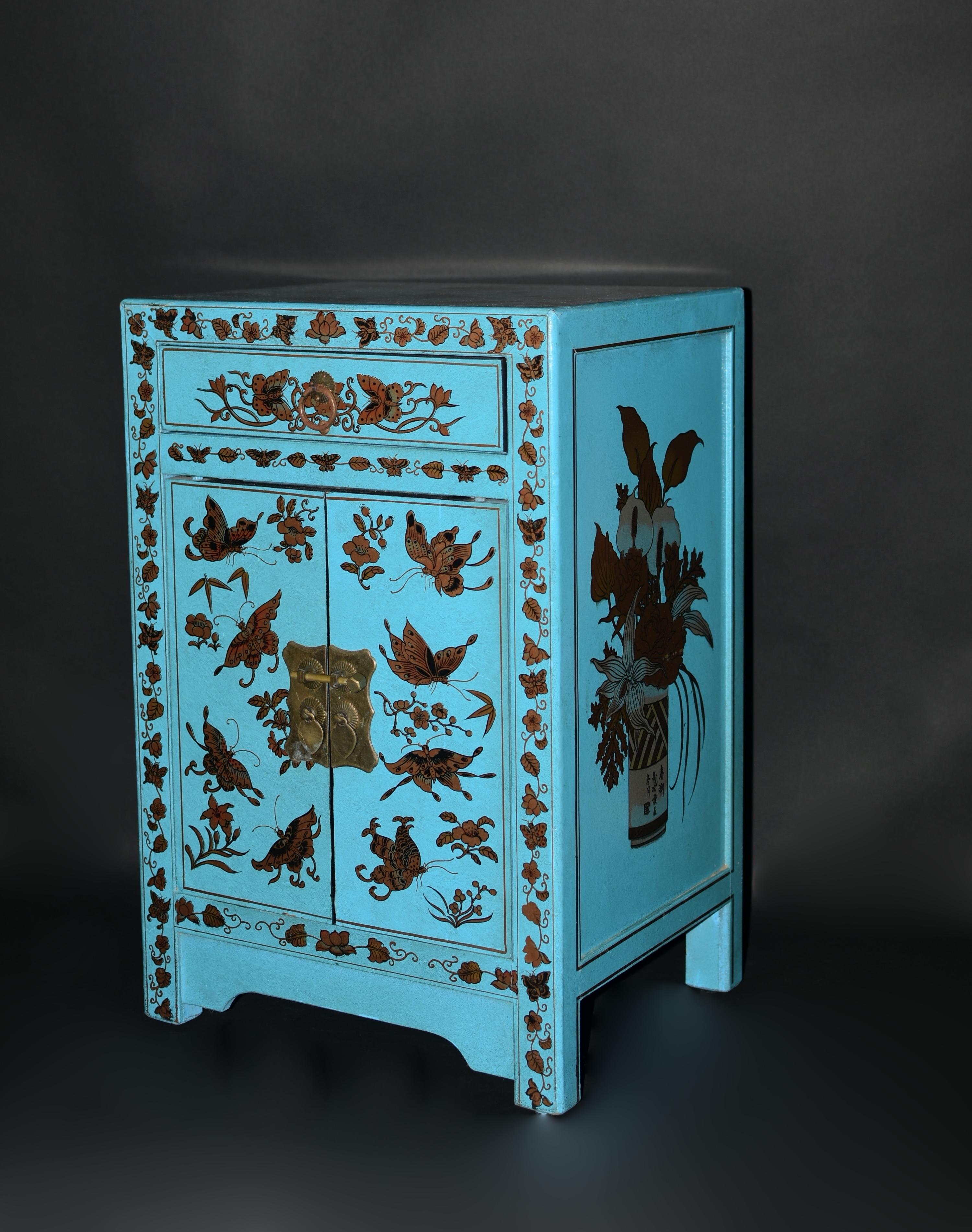 A beautiful hand painted turquoise lacquered cabinet, night stand. Cabinet is hand painted with butterflies and various seasonal flowers such as peonies, begonias, prunus blossoms and lilies. One side of the cabinet features a group of blooming