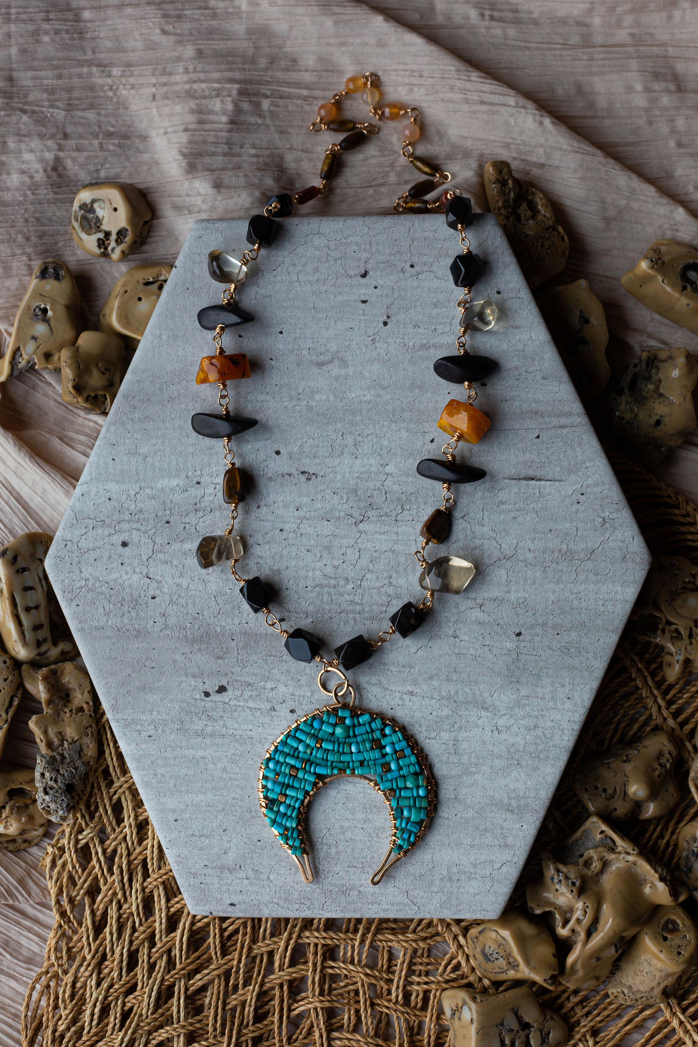 A show stopping artisan crafted piece of genuine jeweler’s brass, various turquoise beads, smokey quartz, black onyx, dark wood, carnelian, tigers eye and vintage butterscotch amber. 18” in overall length, pendant is approximately 3 x 3 inches.