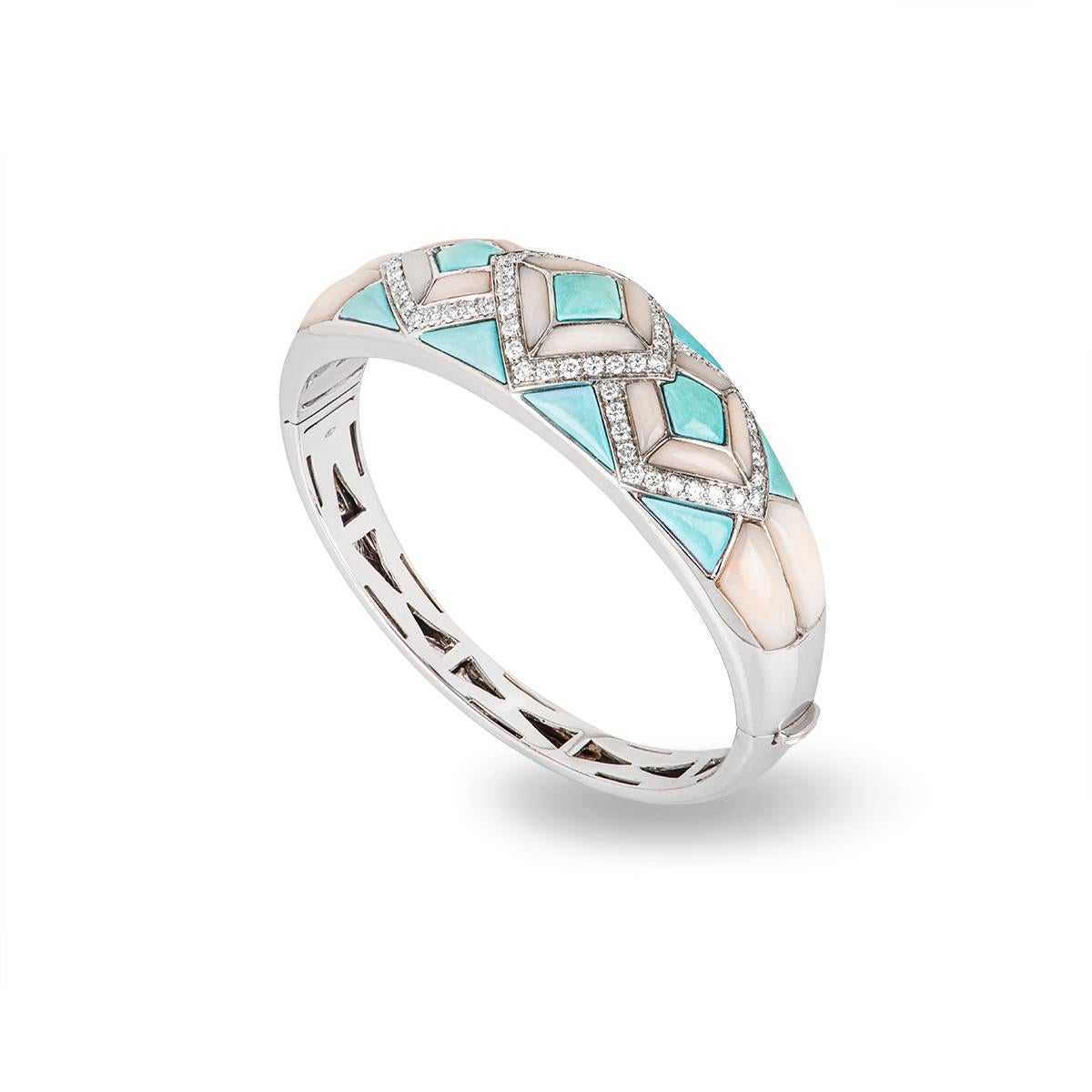 An 18k white gold turquoise, coral and diamond bangle. The bangle comprises of turquoise and coral set in a mosaic pattern with 3 rhombus shapes set with round brilliant cut diamonds. The 68 diamonds have an approximate weight of 2.04ct. The bangle